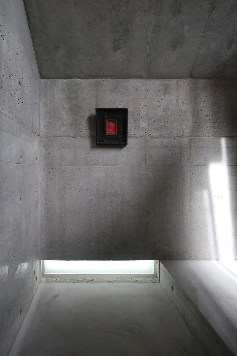 Music Hall in the Sky by Takuro Yamamoto Architects — A concrete stairwell descends toward a ground-level opening, its monolithic board-formed walls creating a geometric passage.