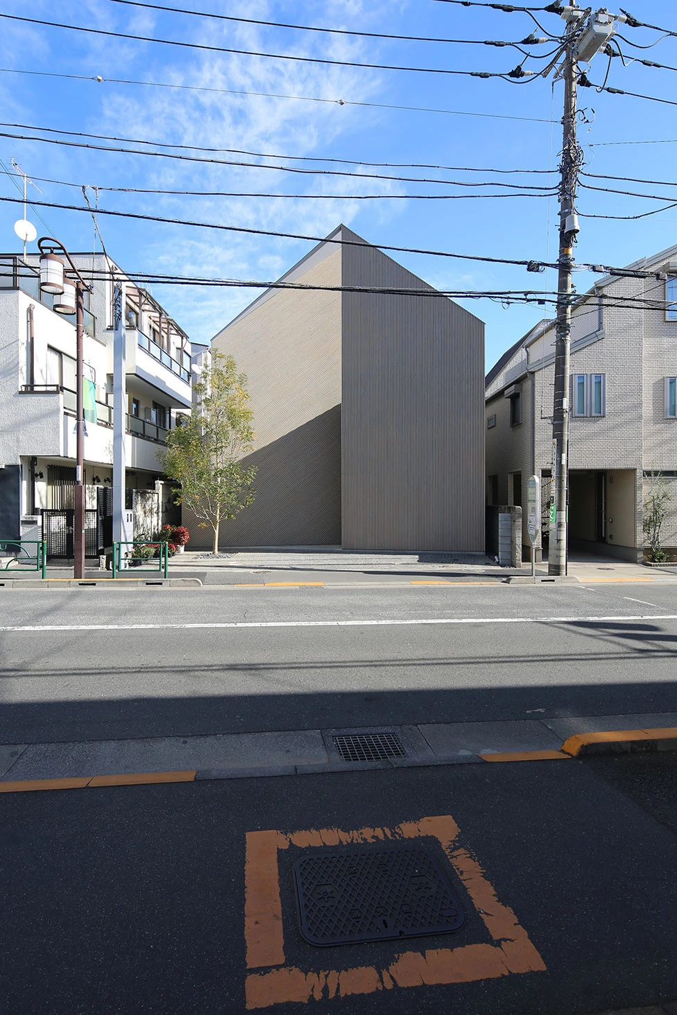 Music Hall in the Sky by Takuro Yamamoto Architects — The monolithic facade of Music Hall in the Sky presents an unbroken corrugated metal surface punctuated by a single recessed entrance portal.