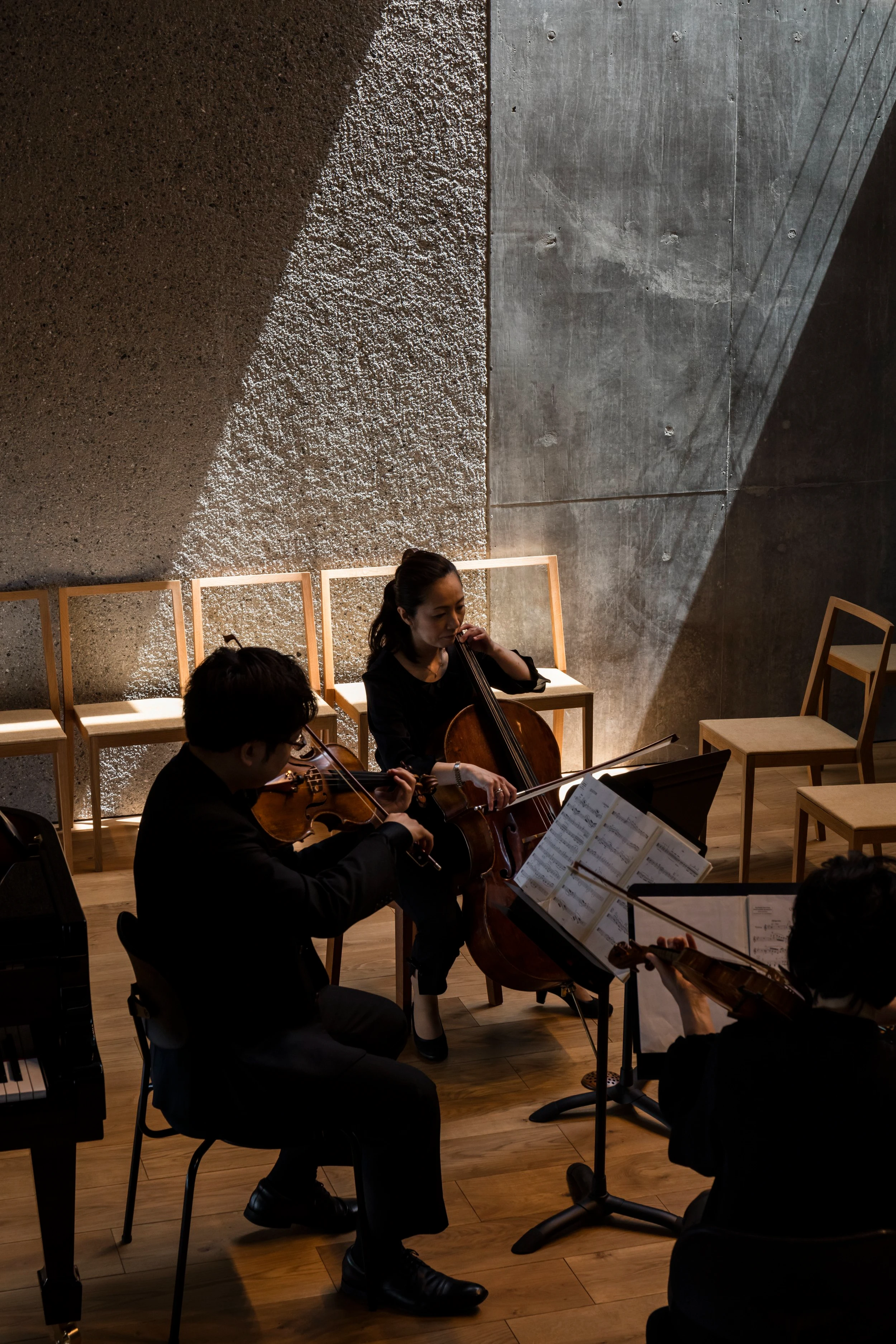 Music Hall in the Sky by Takuro Yamamoto Architects — Two musicians perform in the concert hall's interior, positioned beneath the angular skylight that casts a geometric light shaft across the textured...