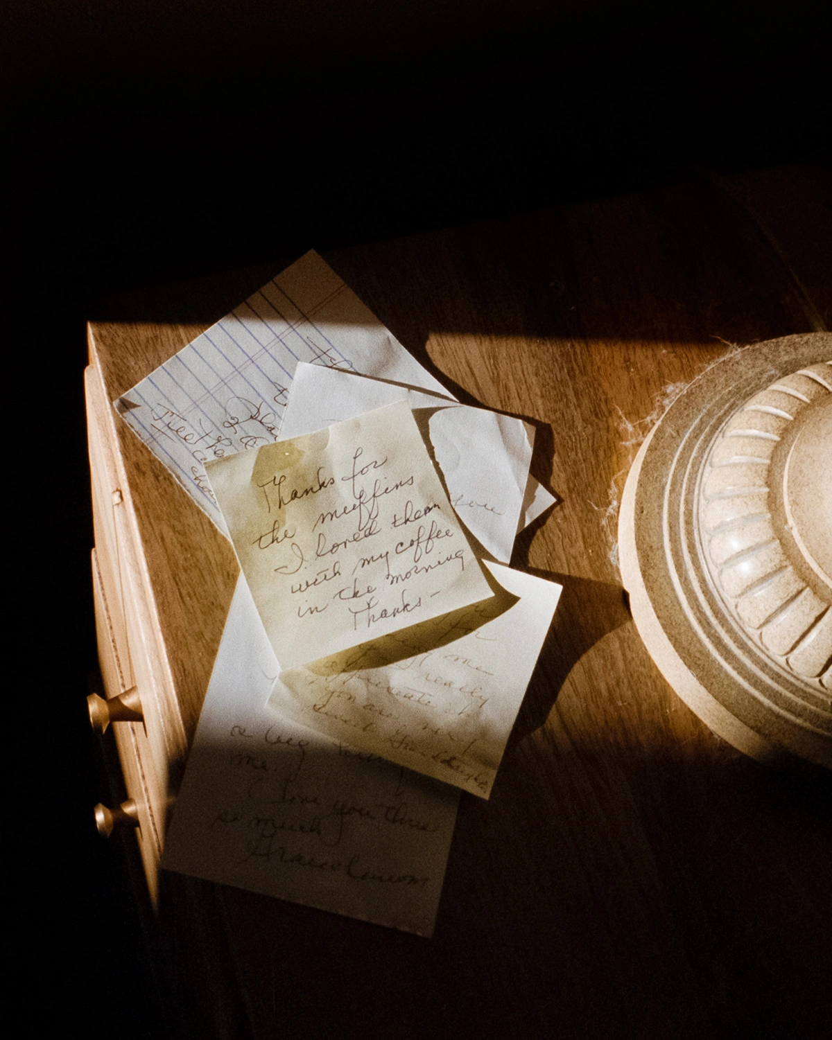 We Keep Swimming, Until We All Reach Home by Jillian Guyette — Overhead view of handwritten correspondence and architectural ephemera arranged on a wooden surface.