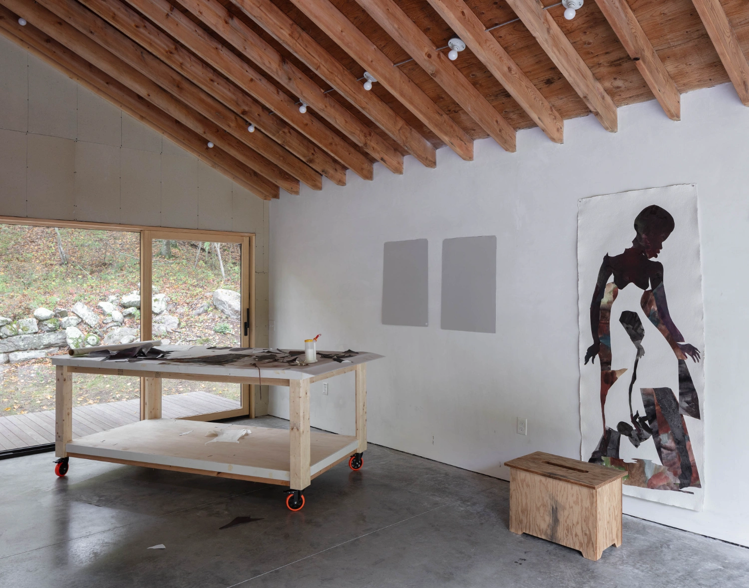 Studio Barn by Worrell Yeung — A working studio interior featuring exposed timber ceiling beams with recessed lighting and concrete flooring.