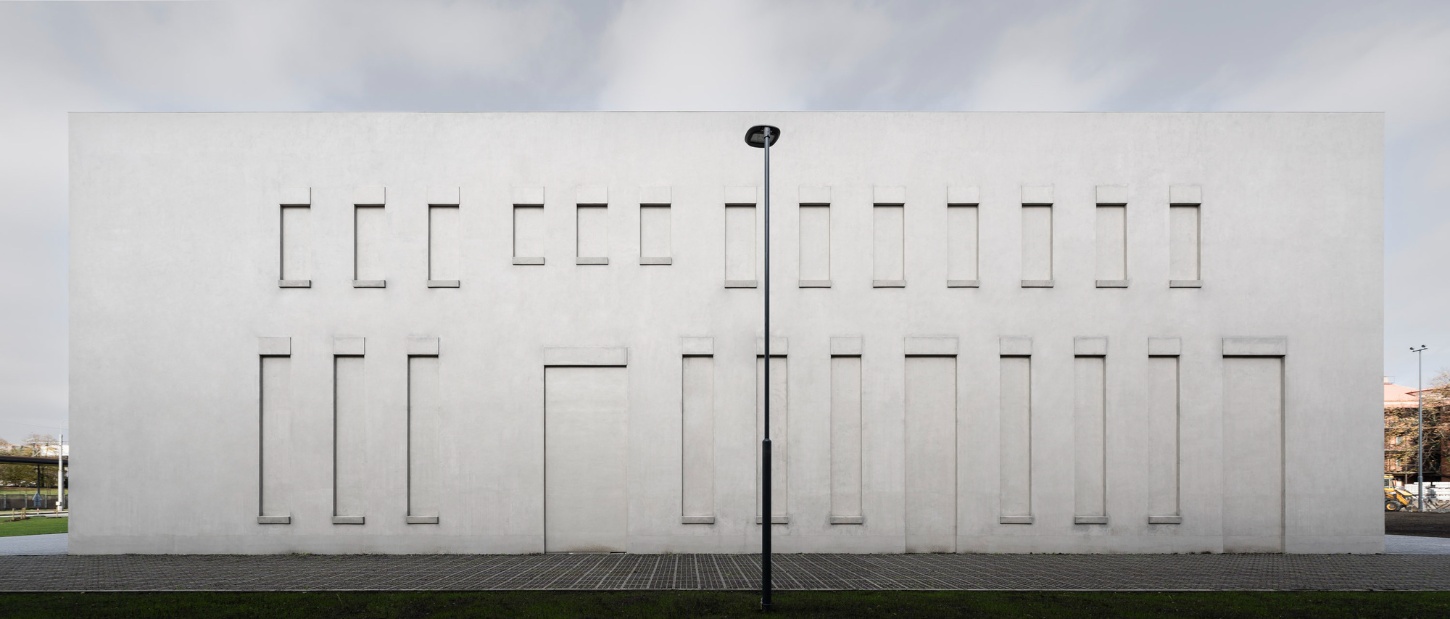 PLATO Contemporary Art Gallery by KWK PROMES — The PLATO Contemporary Art Gallery's primary facade presents a monolithic concrete screen punctuated by recessed rectangular openings arranged in a regular...