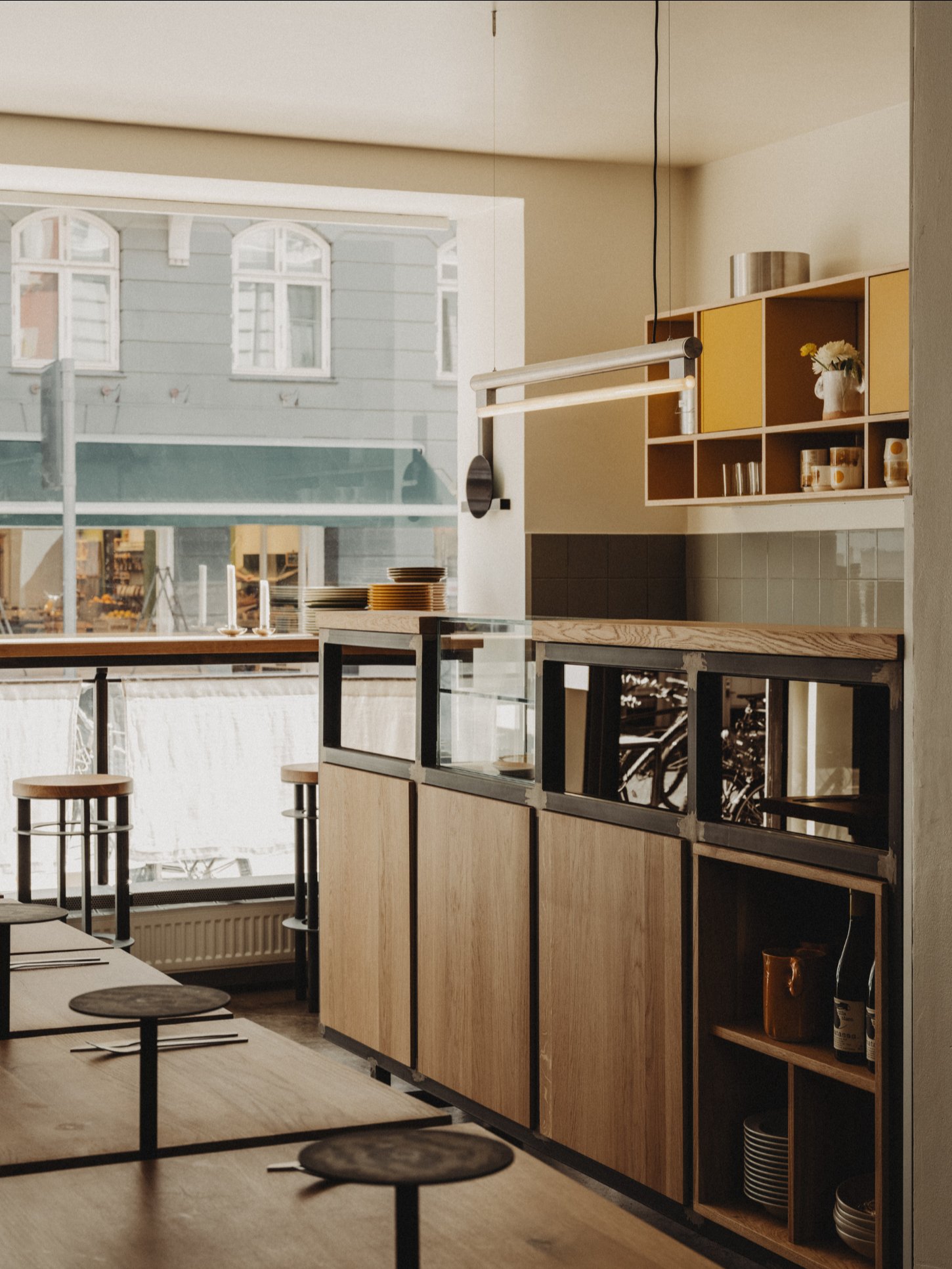 Amator Restaurant by wiercinski-studio — The dining hall features a modular seating system composed of solid oak benches with light-finished tops, arranged in receding perspective toward expansive...