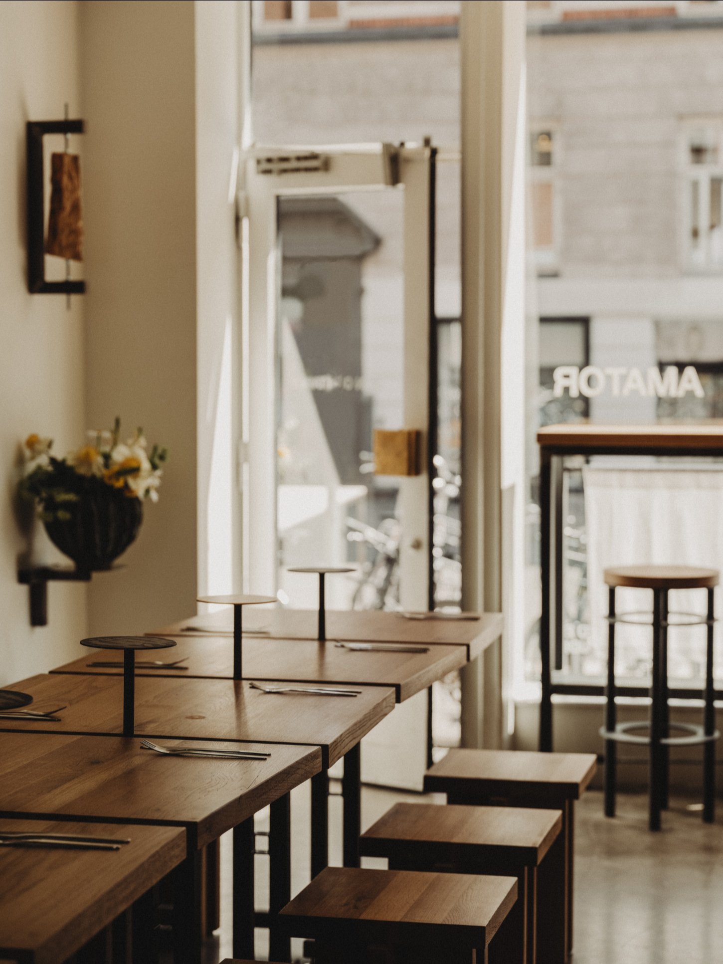 Amator Restaurant by wiercinski-studio — Receding perspective of solid oak benches with light-finished tops arranged in angular formation, their jagged edges creating rhythmic visual breaks across...