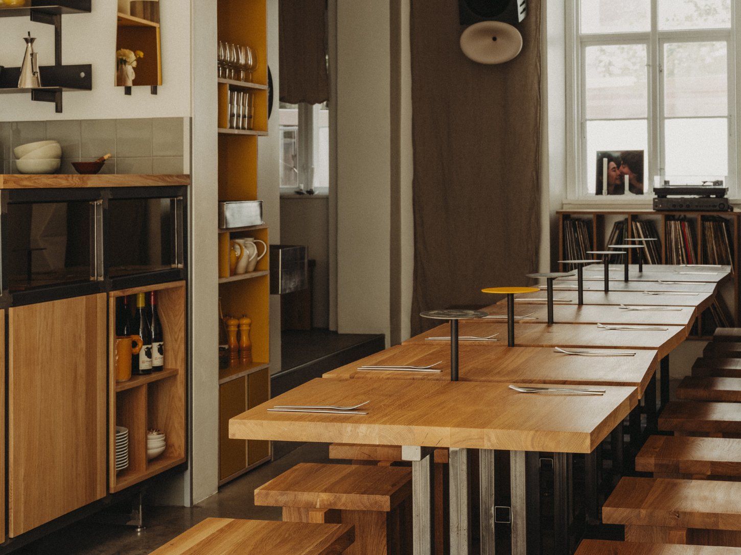 Amator Restaurant by wiercinski-studio — Amator's dining room unfolds in receding perspective, with solid oak tables and benches arranged in staggered alignment.