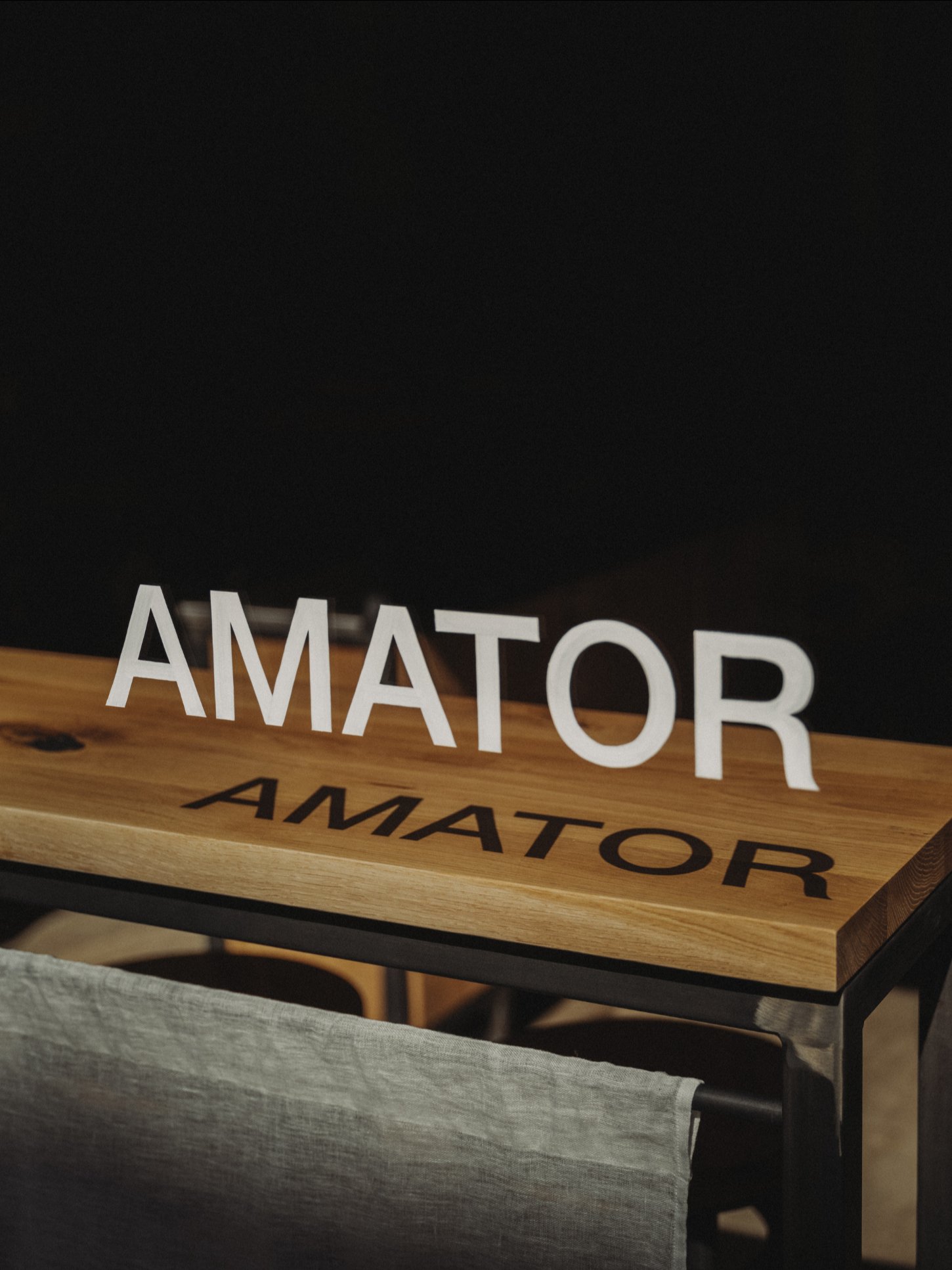Amator Restaurant by wiercinski-studio — A close-up view of Amator's oak dining furniture reveals the precision of its joinery and material hierarchy.