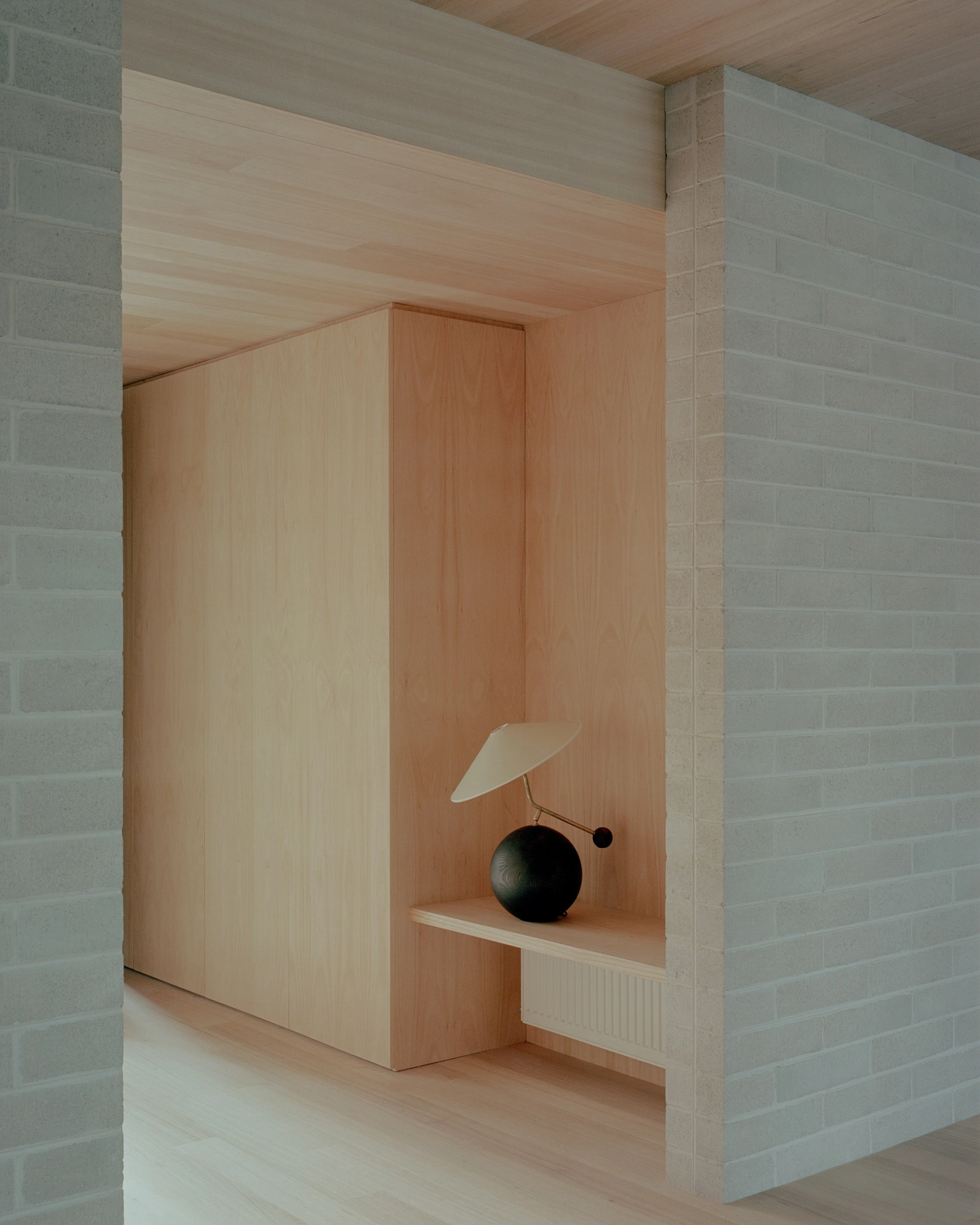 Echo House by Parabolica — A timber-lined alcove reveals a sculptural display nook within Echo House's central spatial arrangement.