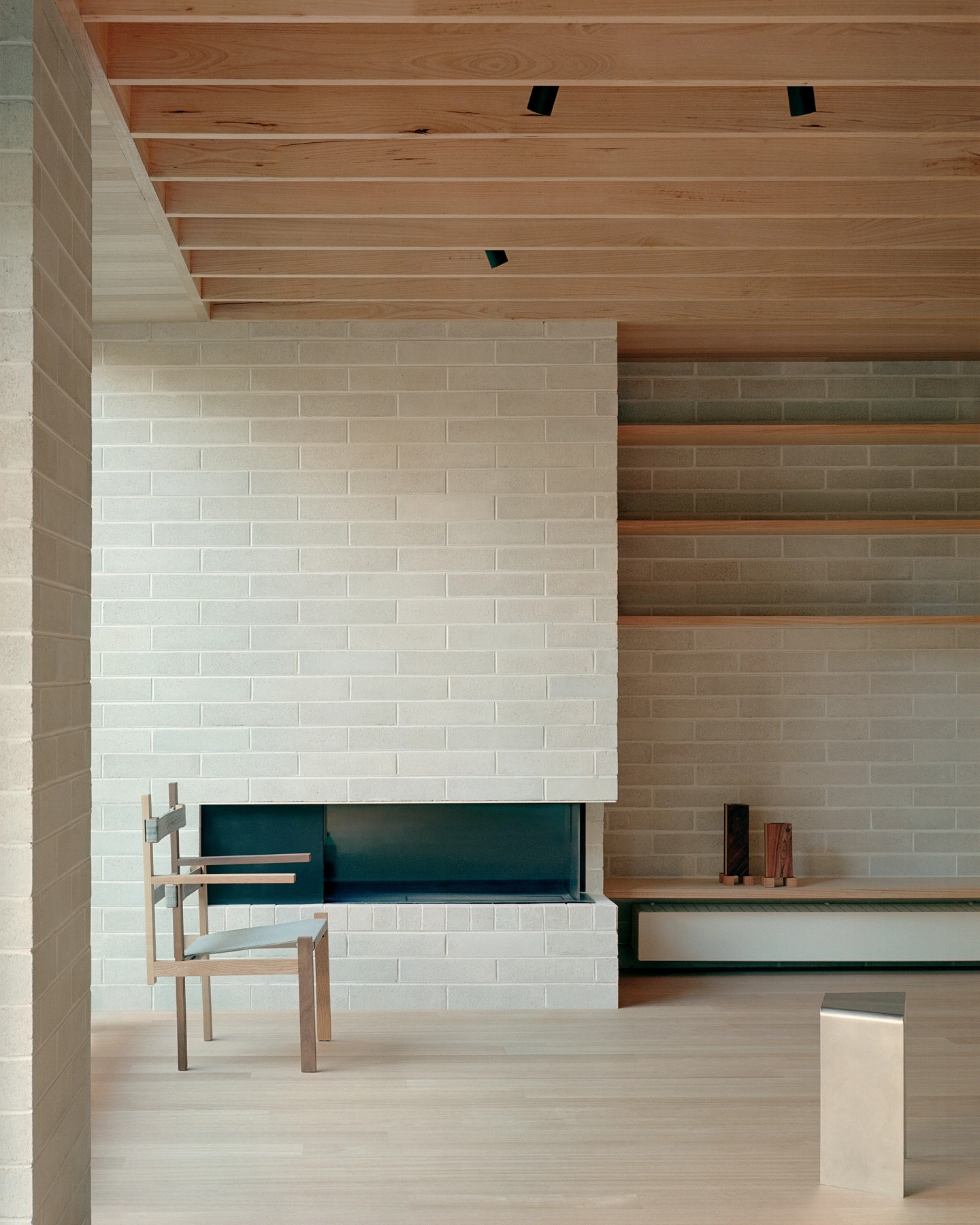 Echo House by Parabolica — A sculptural cream-upholstered lounge chair with matching ottoman sits within a recessed alcove framed by white brick masonry.