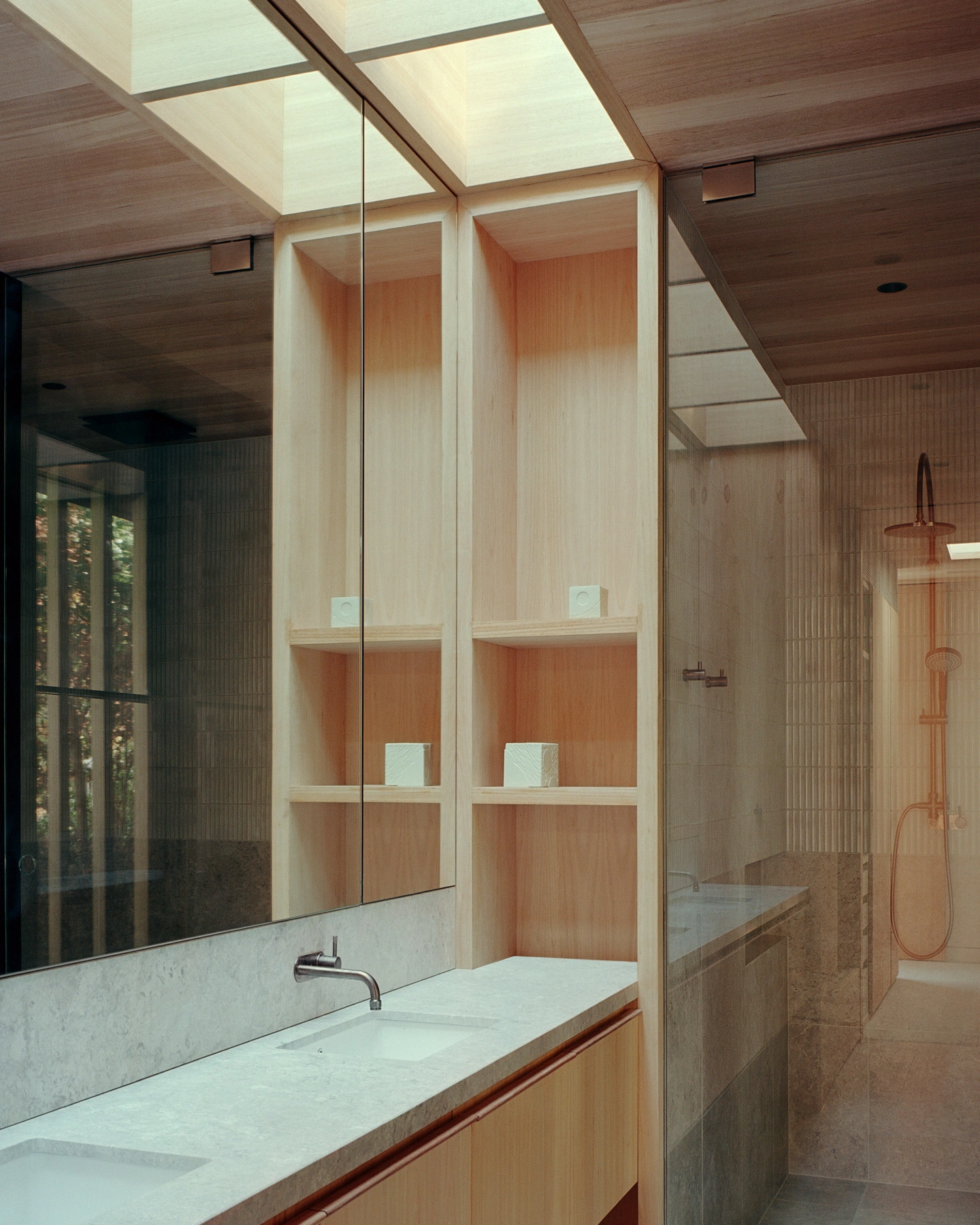 Echo House by Parabolica — The bathroom centers on a double-width mirror reflecting timber-lined storage with horizontal slats in natural wood tones.