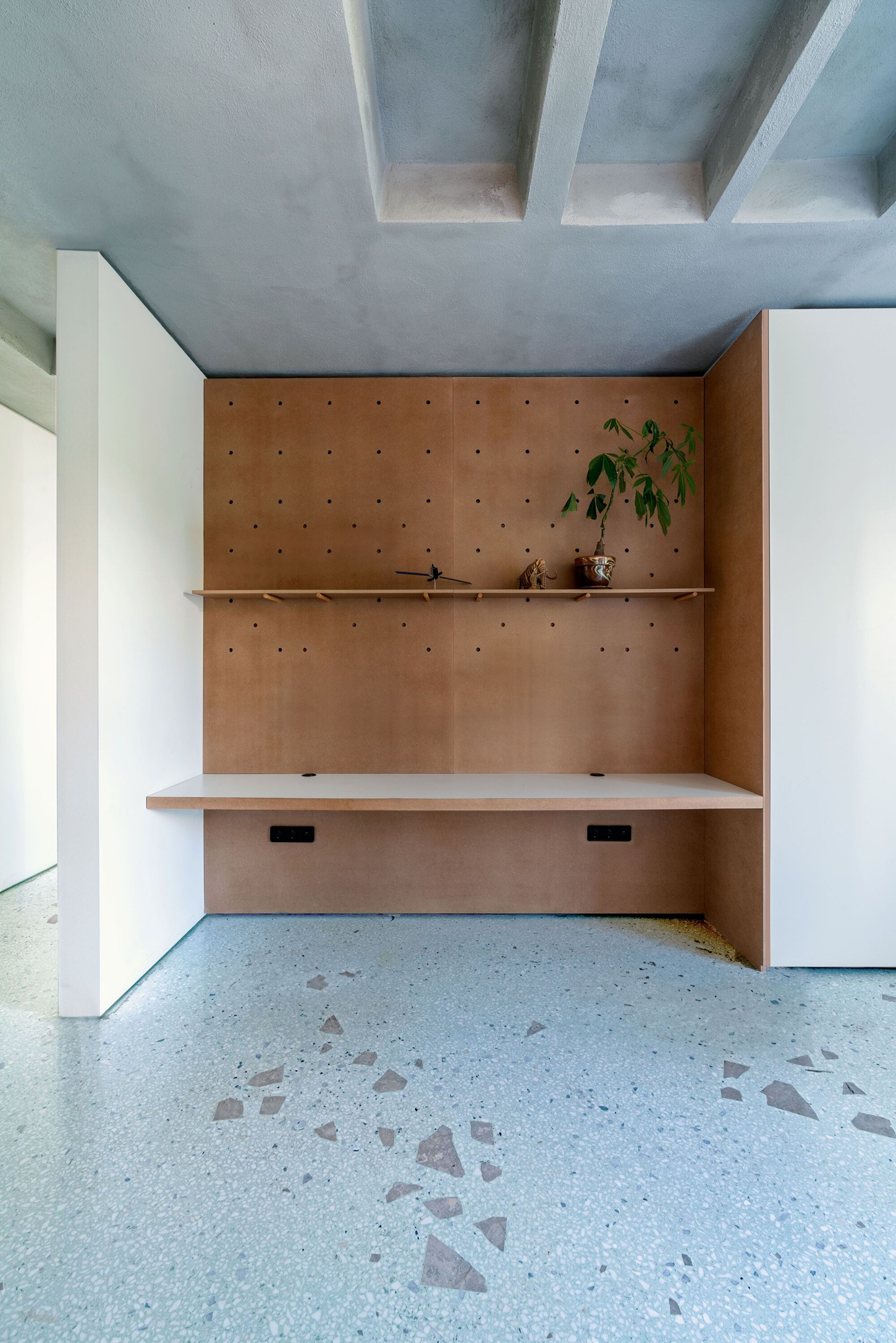 Three Object Apartment by DeMachinas + Elina Loukou — A pivoting storage volume clad in perforated timber plywood dominates this compact kitchen alcove.