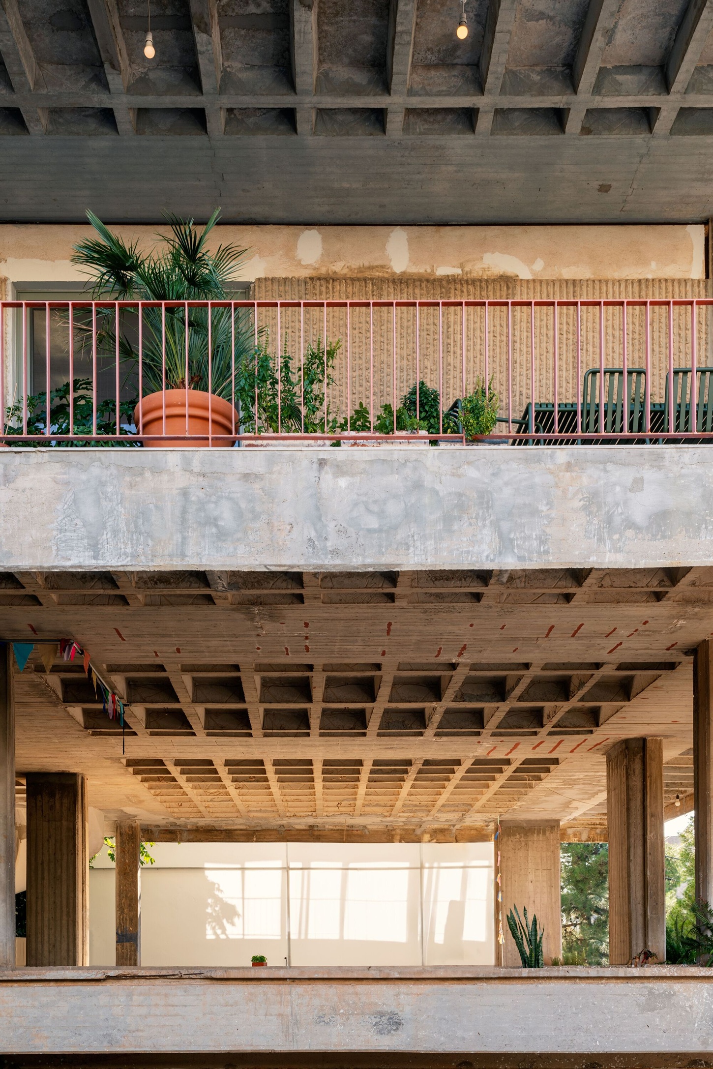 Three Object Apartment by DeMachinas + Elina Loukou — Upper-level terrace of the Three Object Apartment reveals the circular kitchen island as sculptural centerpiece, its terracotta tile wrapping and dark wood...