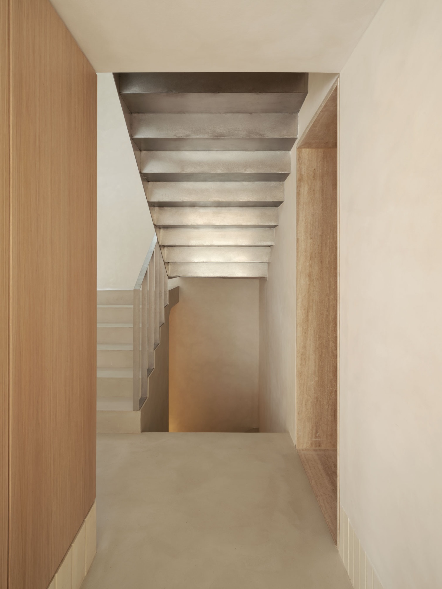 Casa SO by Studio DIIR — A narrow timber-lined passage extends toward a distant bedroom flooded with warm natural light.