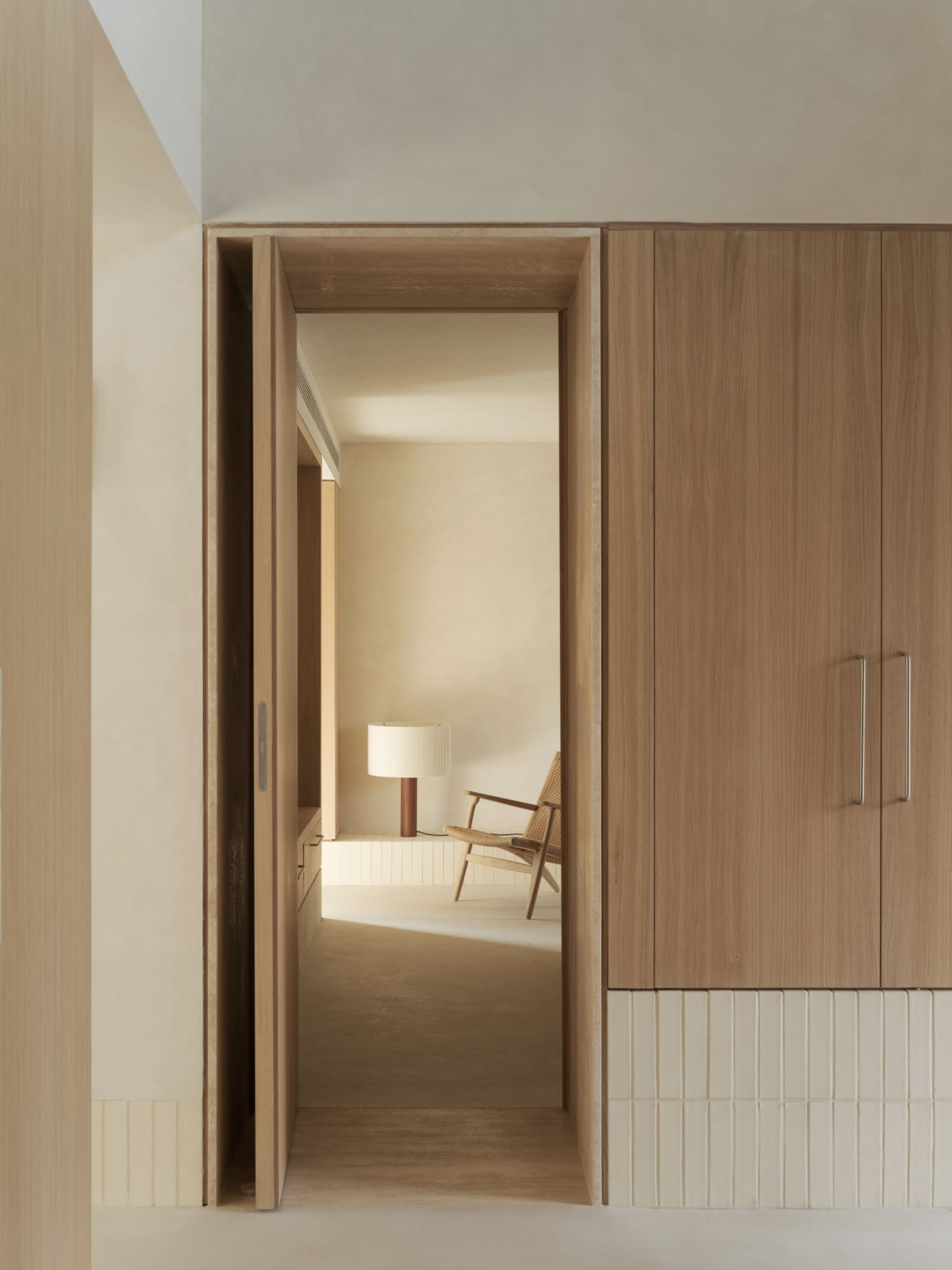 Casa SO by Studio DIIR — A timber-framed passage opens into a distant bedroom, its depth accentuated by recessed layering at the threshold.