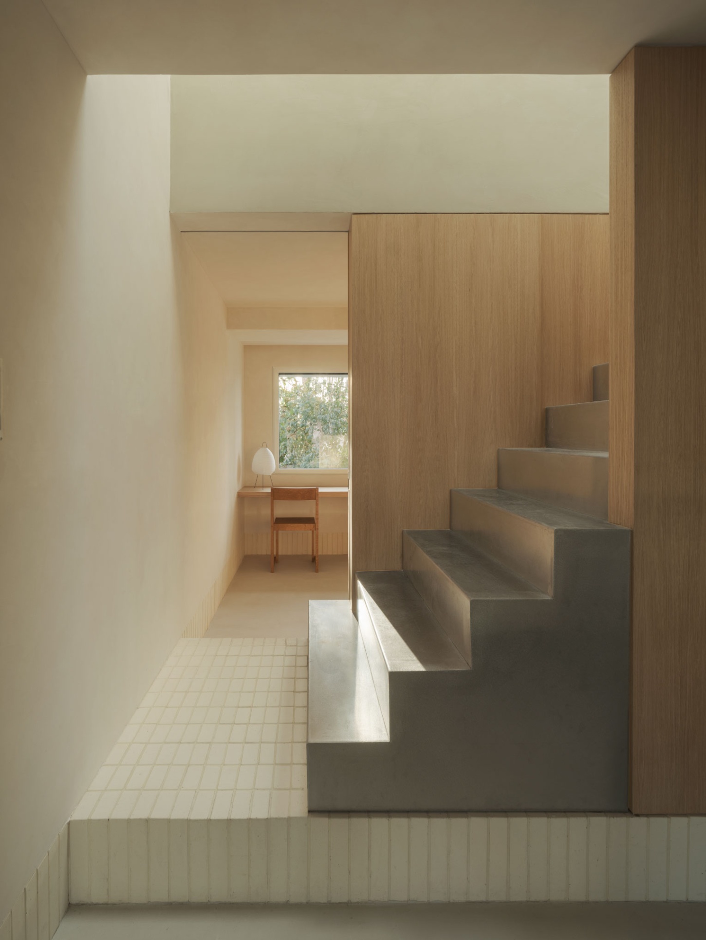 Casa SO by Studio DIIR — A compressed corridor transitions toward spatial release, its pale plaster walls framing a timber-clad stair element on the right.