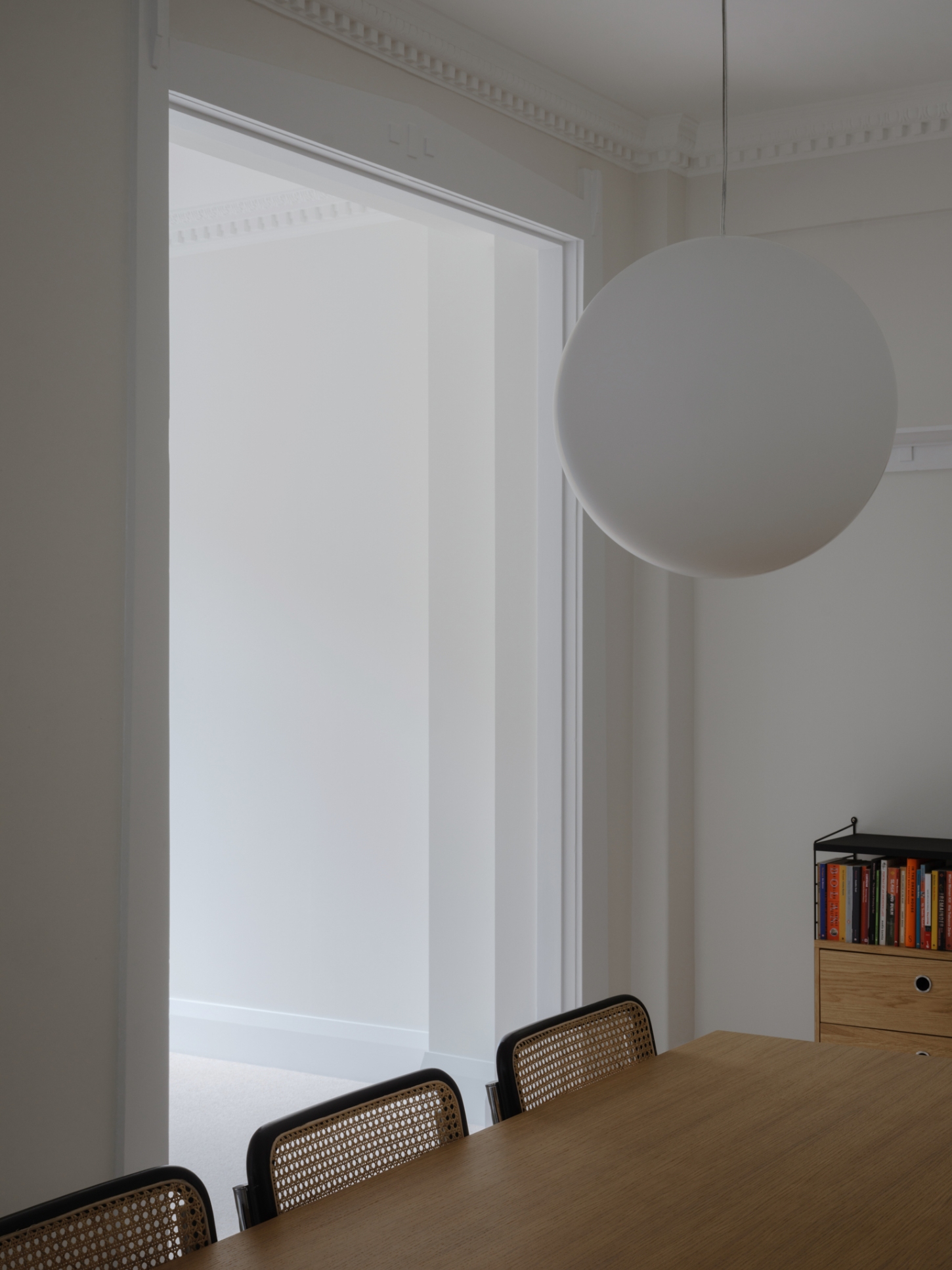 Onslow Gardens Apartment by Youssofzay Hart — A dining threshold framed by white architrave creates a layered passage between spaces.