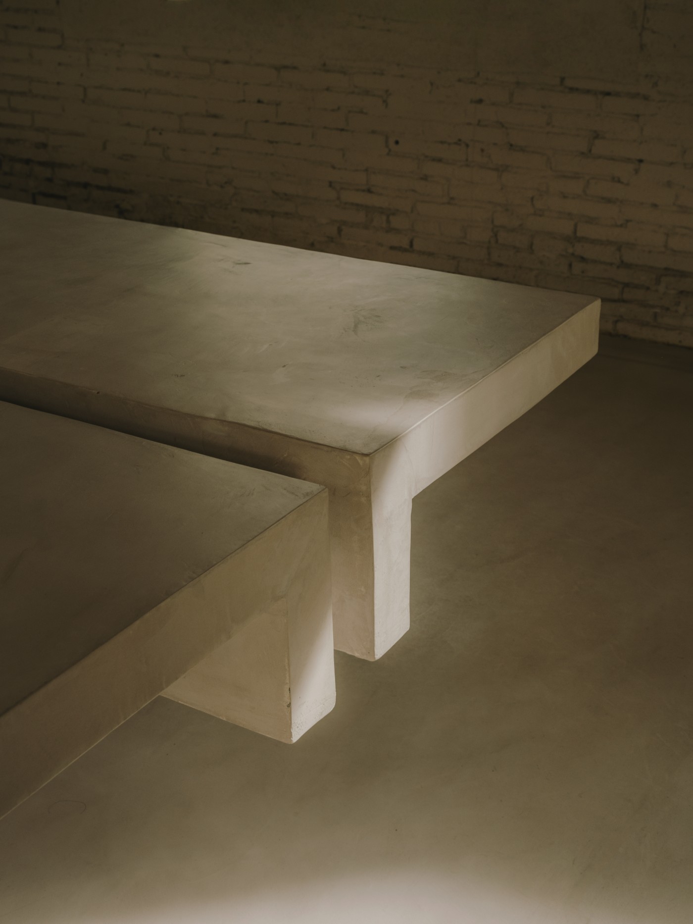Blow Studio by Isern Serra — A monolithic cream-colored concrete bench cantilevers from the recessed circular pit, its volumetric form casting sharp shadows against the polished...