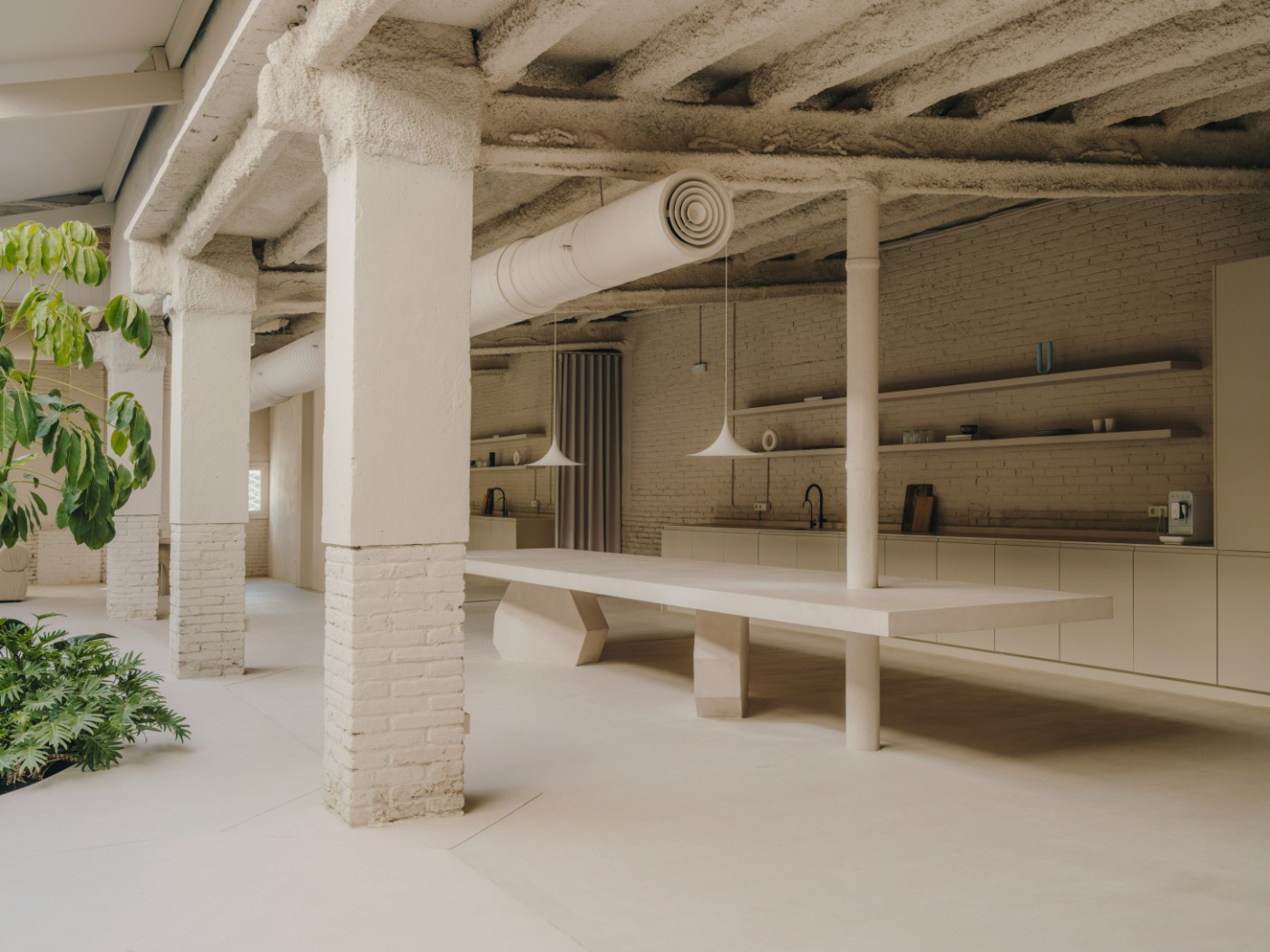 Blow Studio by Isern Serra — A monolithic concrete workspace anchored by a sculptural curved bench recessed into the polished floor.