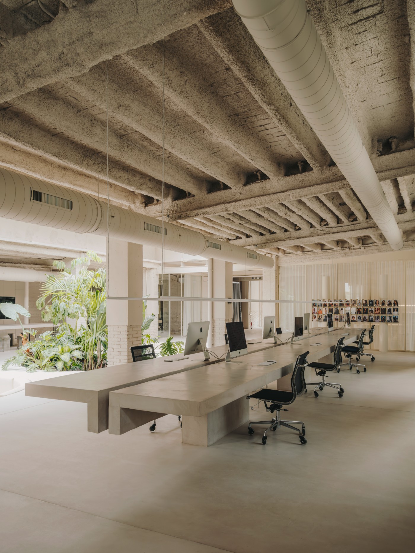 Blow Studio by Isern Serra — A linear workspace anchored by monolithic concrete desk volumes, their sculptural forms rising from polished concrete flooring.