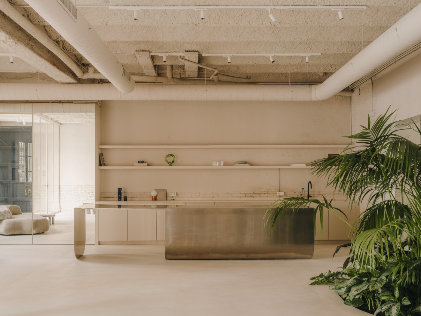 Blow Studio by Isern Serra — A monolithic brass cylindrical sink island anchors the studio's open plan, its metallic surface reflecting the zenithal light from above.