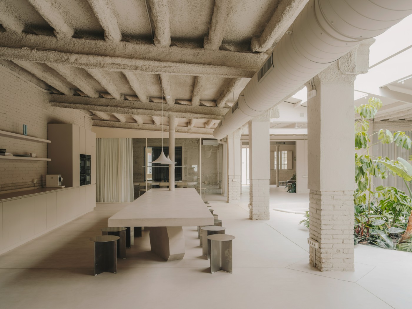 Blow Studio by Isern Serra — A recessed circular seating pit dominates the polished concrete floor, its cream-colored upholstered bench wrapping continuously around the perimeter.