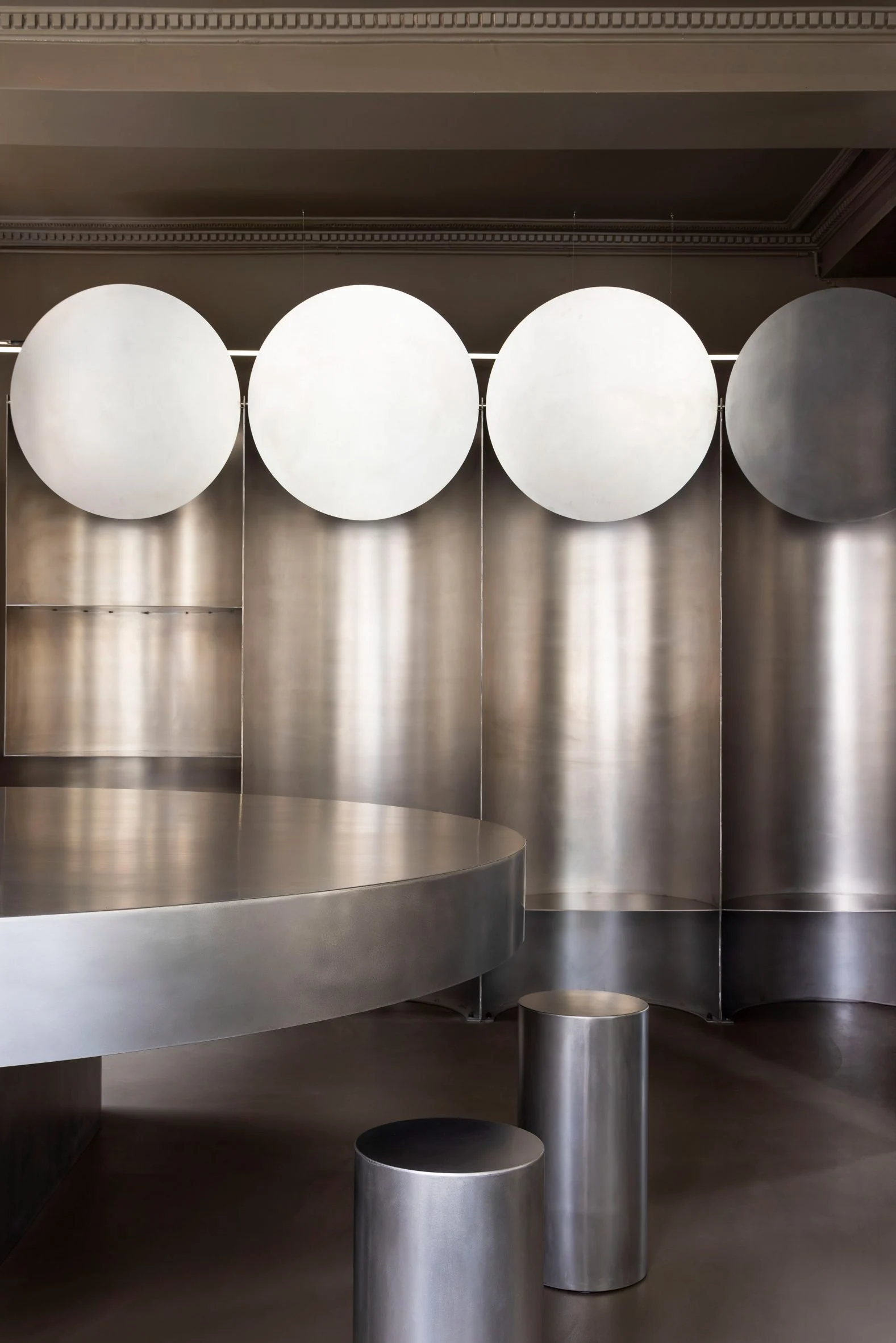 Simple Coffee by Mur Mur Architects — A single-room café interior dominated by brushed stainless steel surfaces and geometric forms.