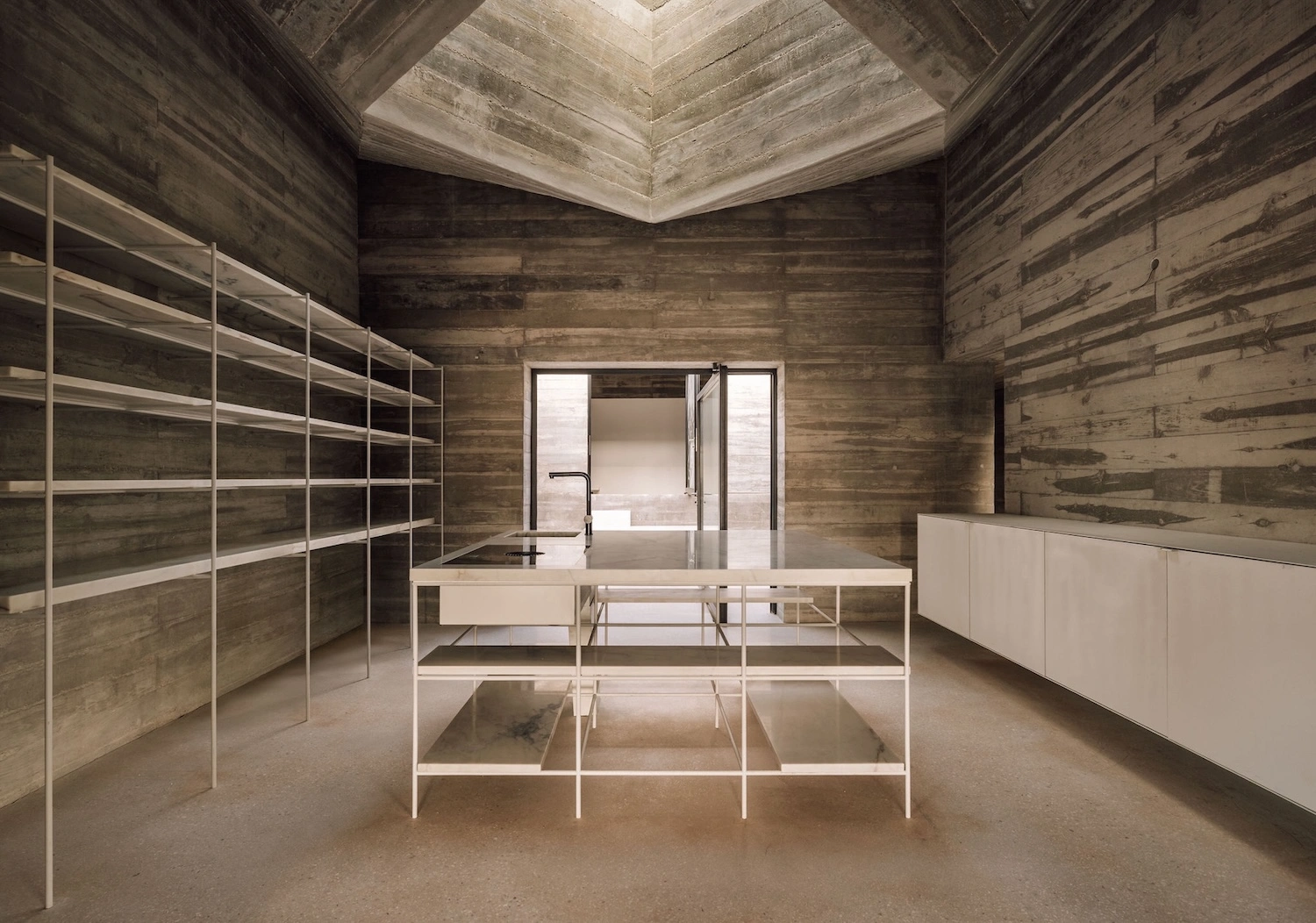 Frame House by Pedro Domingos Arquitectos — Interior view of Frame House reveals a minimalist storage system composed of white-painted metal shelving units arranged in geometric grids across a...