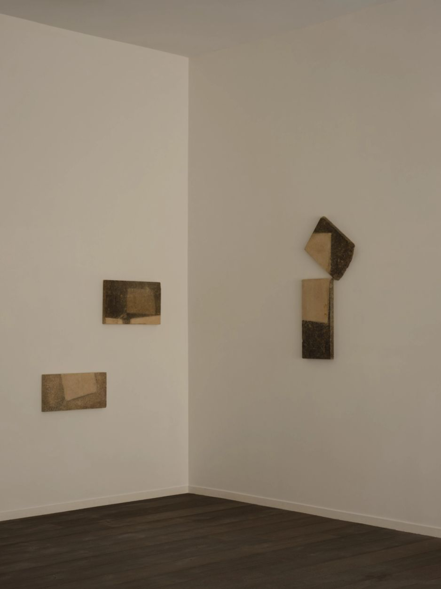 ‘Untitled’ by JAMESPLUMB & Garcé Dimofski at Francis Gallery — Five stone fragments mounted across two white walls in a corner gallery space, their surfaces divided between weathered tan sections and darker charred or...