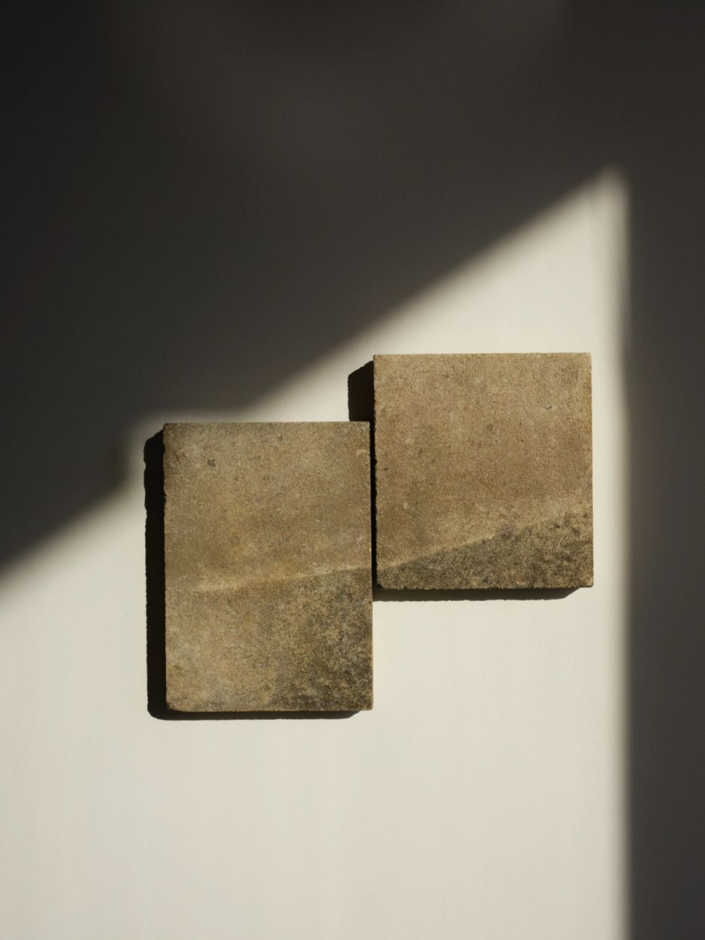 ‘Untitled’ by JAMESPLUMB & Garcé Dimofski at Francis Gallery — Two weathered stone blocks mounted on a white wall, positioned at staggered heights in an asymmetric arrangement.