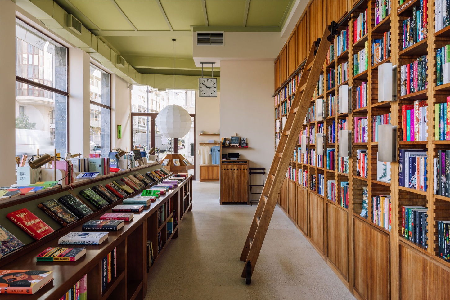Good Company Books by Studio PIM — A timber-lined corridor lined with honey-brown oak shelving stretches toward the storefront glazing.