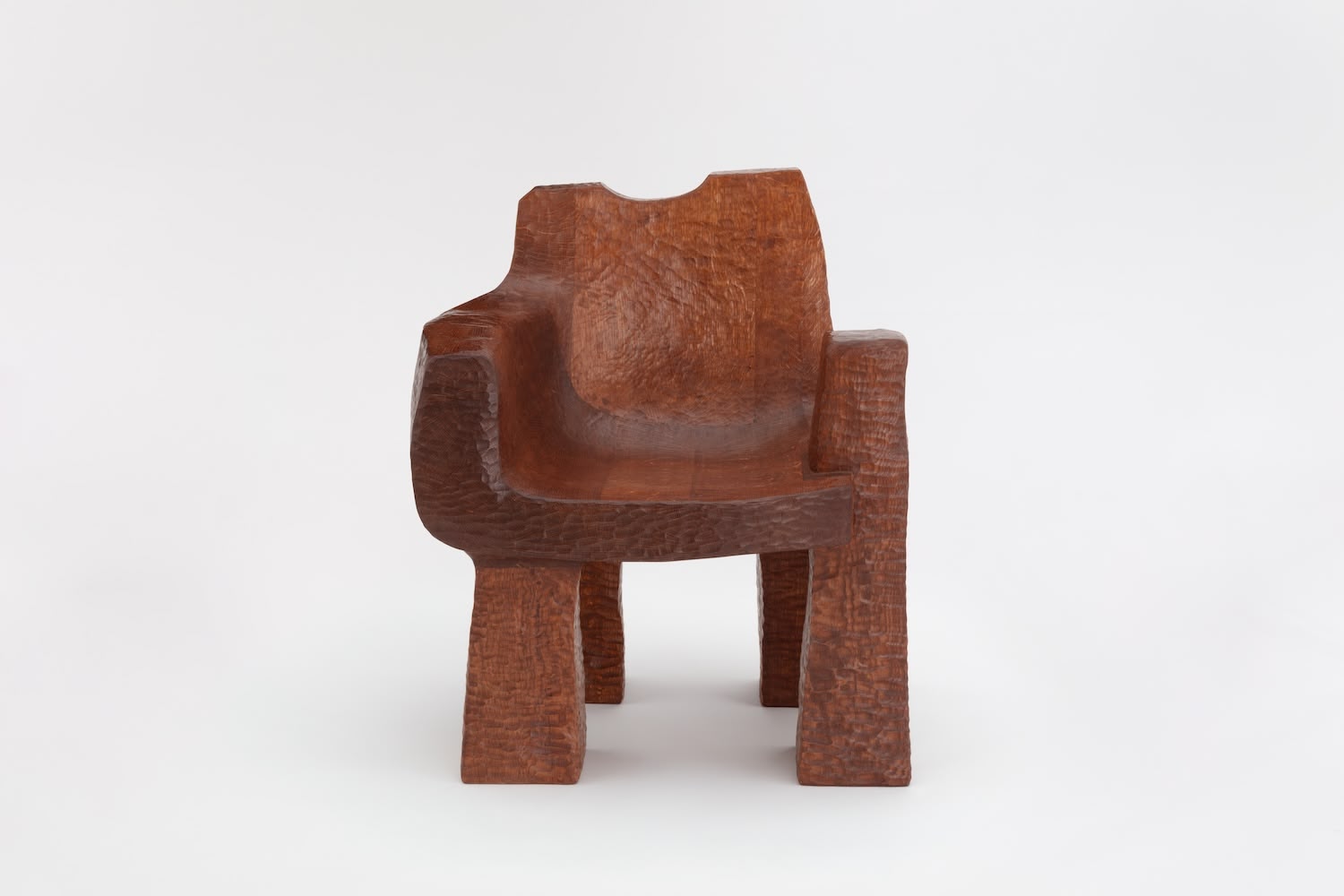 Cairn Chair by Faye Toogood — Carved from solid English oak, the Cairn Chair presents a monolithic wooden form dominated by a deep, hollowed seat cavity with undulating walls.