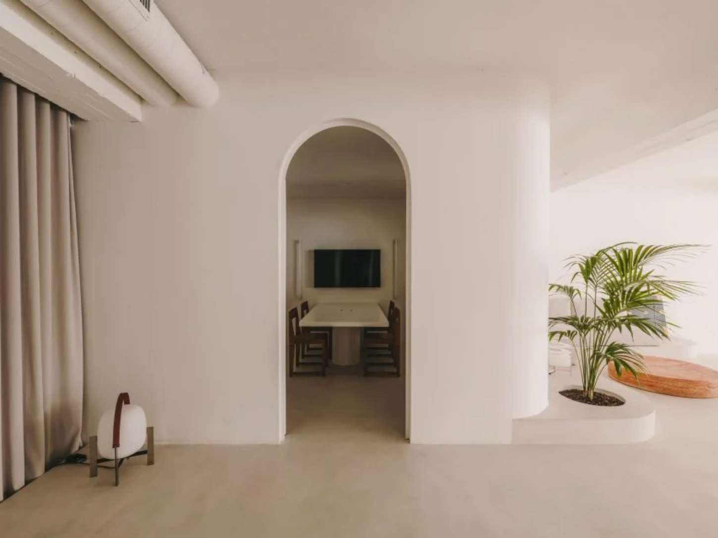 Isern Serra Studio — A 200-square-meter studio interior defined by whitewashed plaster walls and an arched passage that frames a recessed workspace.