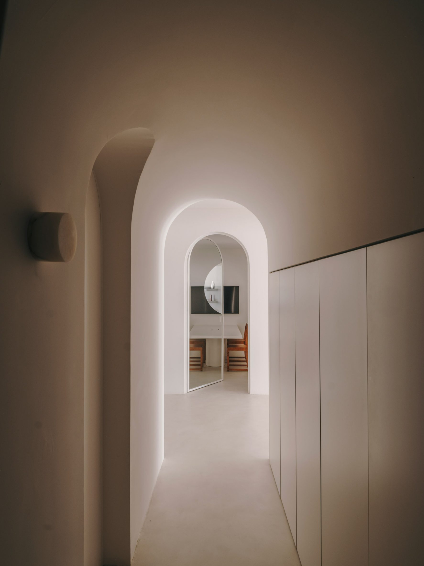 Isern Serra Studio — A whitewashed corridor with arched ceiling creates a linear perspective toward a glazed doorway.