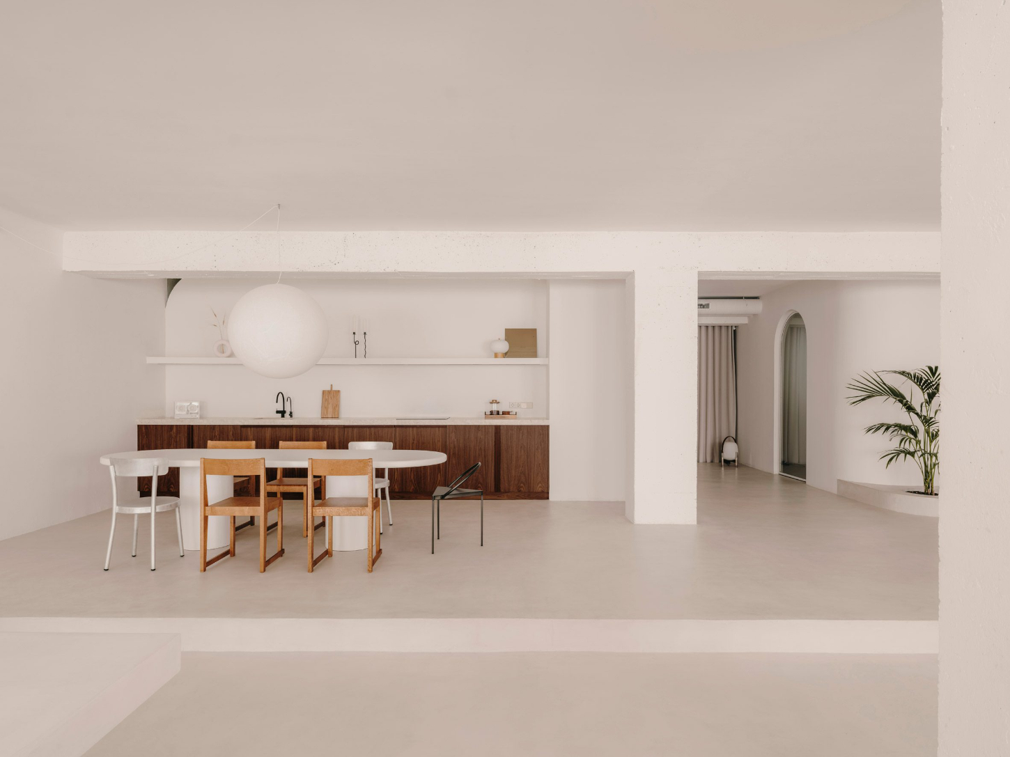 Isern Serra Studio — A 200-square-meter open-plan interior anchored by a walnut-clad kitchen island with integrated sink and cantilevered counter.