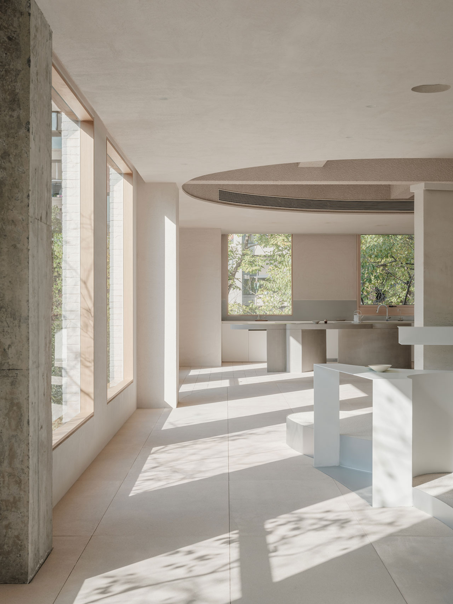 JIA Garden by Mountain Soil — A showroom interior flooded with overhead natural light casting sharp geometric shadows across cream and tan tile flooring.