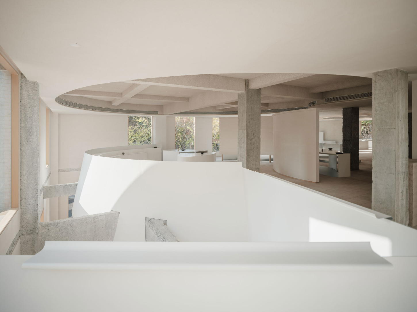 JIA Garden by Mountain Soil — A showroom interior featuring a curved white display counter in the foreground, with a secondary rounded reception desk visible beyond.