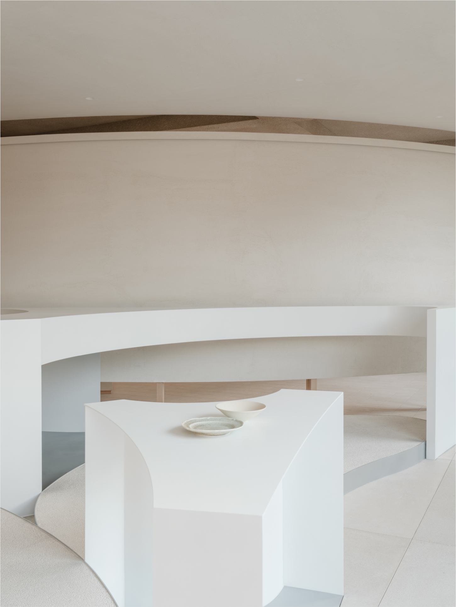 JIA Garden by Mountain Soil — A white monolithic display table with organic leaf-shaped form occupies the center of a minimalist interior gallery space.