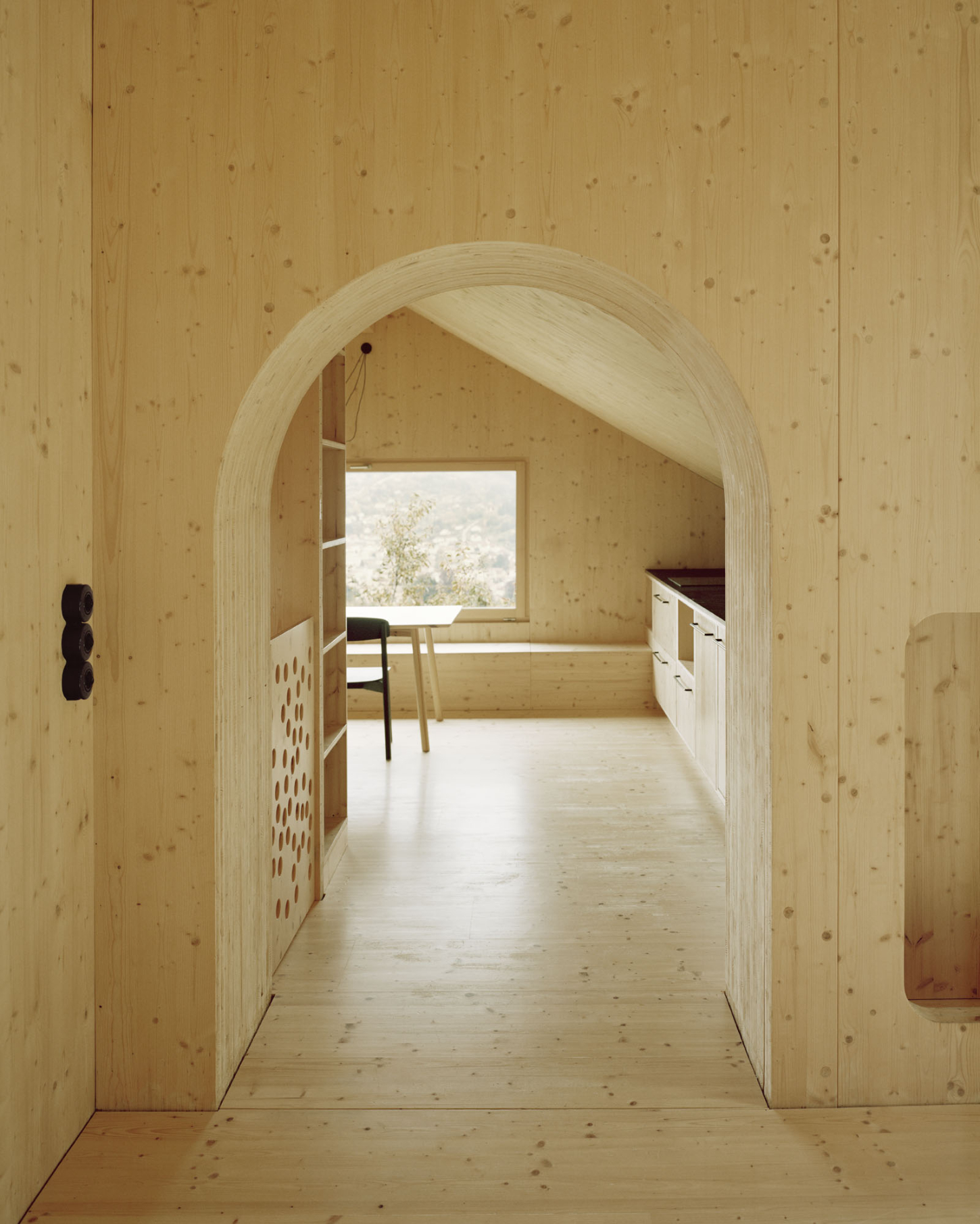 Maison Hiltiti captured by Rasmus Norlander by Atelier Ordinaire — A corridor framed by a generous timber arch reveals layered spatial depth within the CLT timber construction.