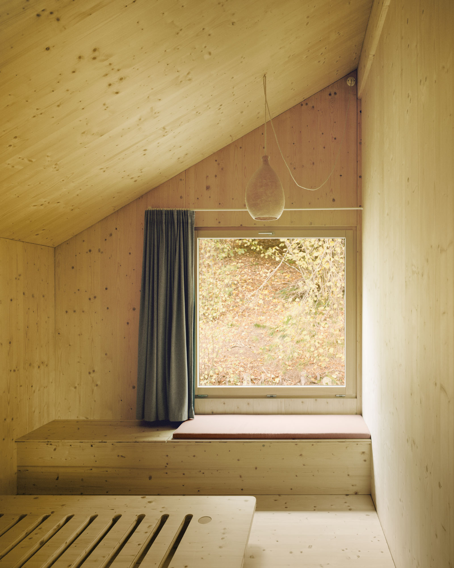 Maison Hiltiti captured by Rasmus Norlander by Atelier Ordinaire — A timber-clad interior nook demonstrates cross-laminated construction through visible ceiling and wall planes of pinewood with knot patterns.