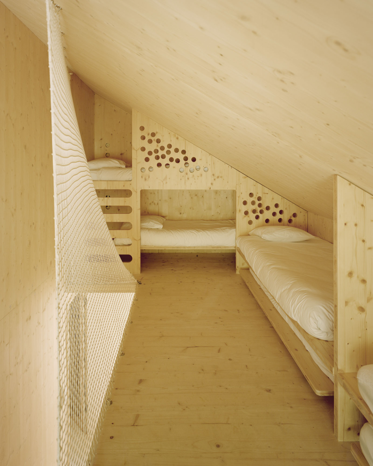 Maison Hiltiti captured by Rasmus Norlander by Atelier Ordinaire — A narrow timber bedroom beneath a pitched roof demonstrates efficient spatial planning within the weekend retreat.