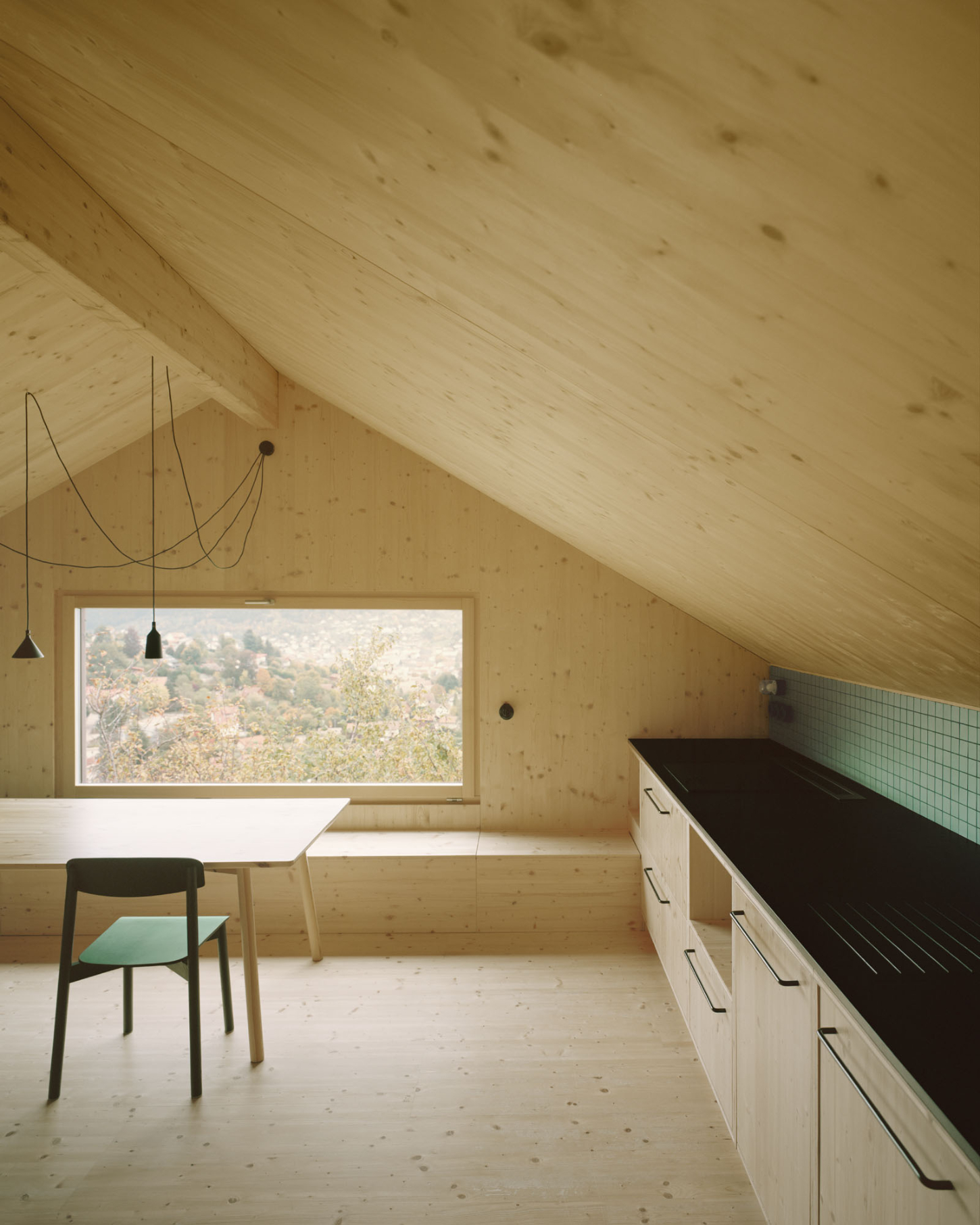 Maison Hiltiti captured by Rasmus Norlander by Atelier Ordinaire — A pitched timber attic interior in cross-laminated construction, with walls and ceiling planes of pale pine marked by knots and grain variation.