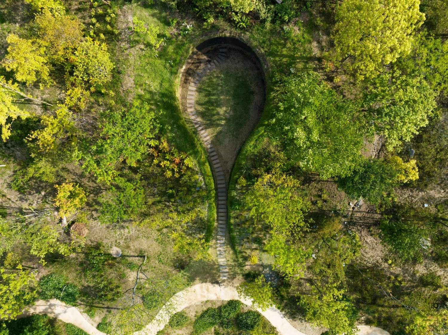 Library in the Earth by Hiroshi Nakamura & NAP — Aerial view of the Library in the Earth's recessed entrance, framed by dense deciduous canopy.