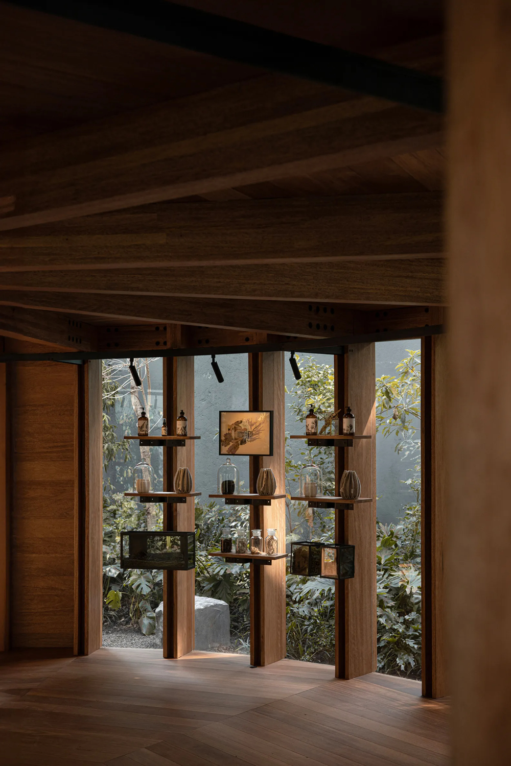 Xinú Marsella by Esrawe Studio by Estrawe Studio — A timber pavilion showcases a radial shelving system with cantilevered wooden arms extending from central vertical supports, displaying ceramic vessels and...