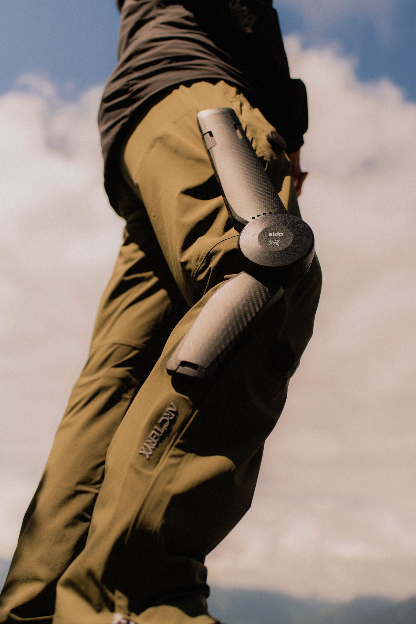 MO/GO Pants with Exoskeleton by Arc'teryx + Skip — A low-angle photograph captures the MO/GO exoskeleton pants against a clouded sky, isolating the mechanical components through compositional framing.