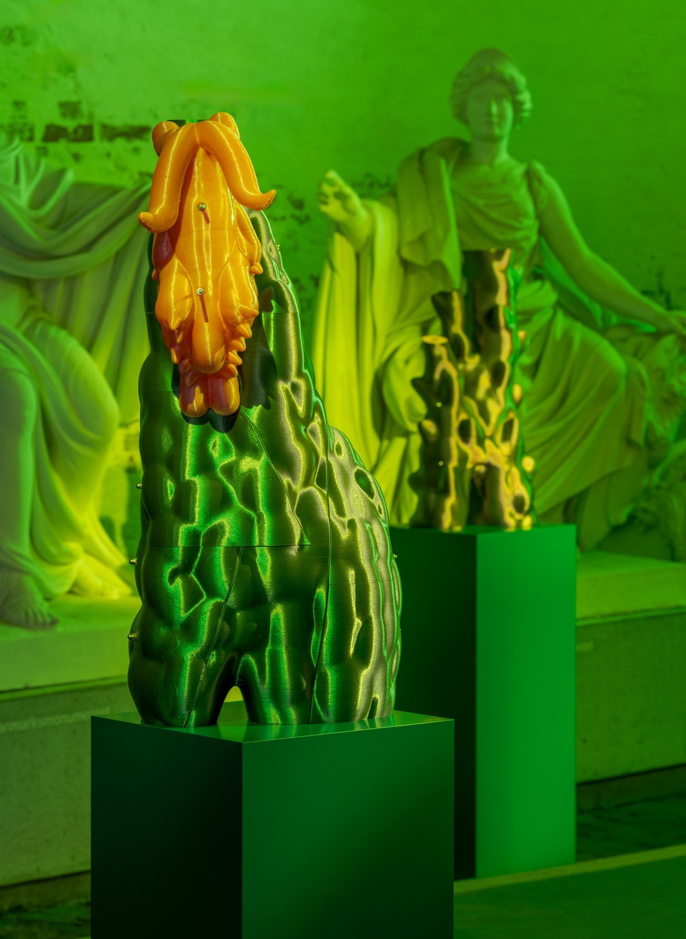 Techno Mythologies by Wang & Söderström at Christian IV’s Brewery — A ceramic cactus form with textured surface sits atop a dark green cubic plinth within a monochromatic lime-green gallery environment.