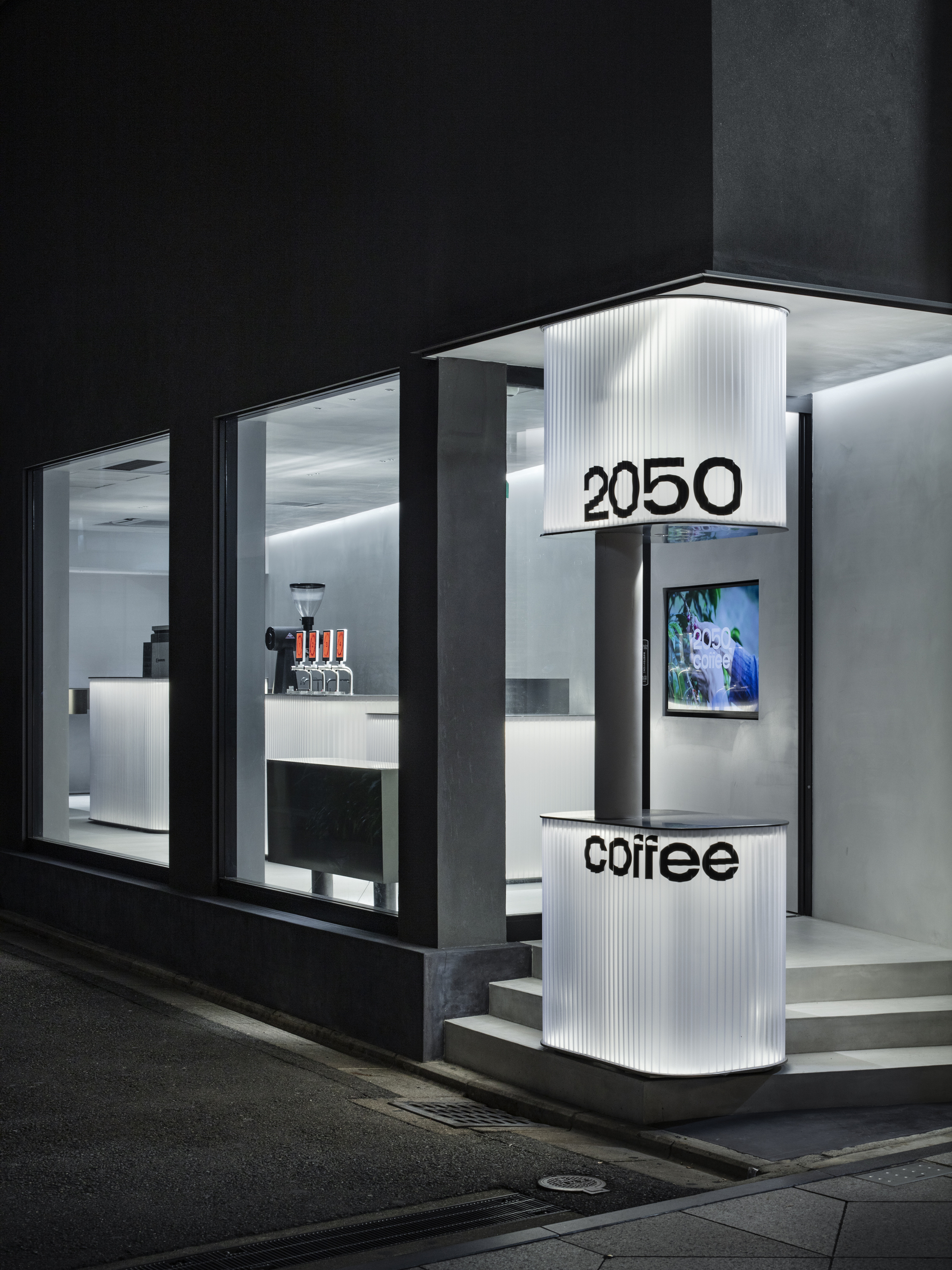 2050 Coffee Shop by TEKI Design — A compact coffee shop storefront clad in translucent corrugated polycarbonate panels with integrated LED illumination, creating a luminous envelope against...