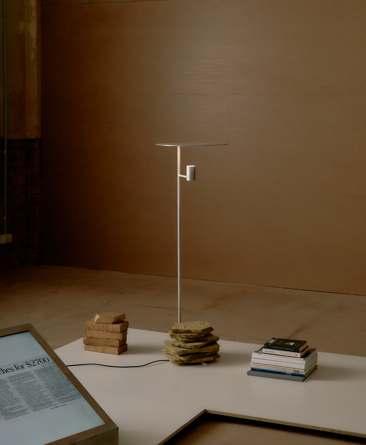 'Call Out' by DO WORKS — A functional lamp constructed from stacked timber blocks as its base, supporting a thin steel pole with an asymmetrically positioned cylindrical arm fixture...