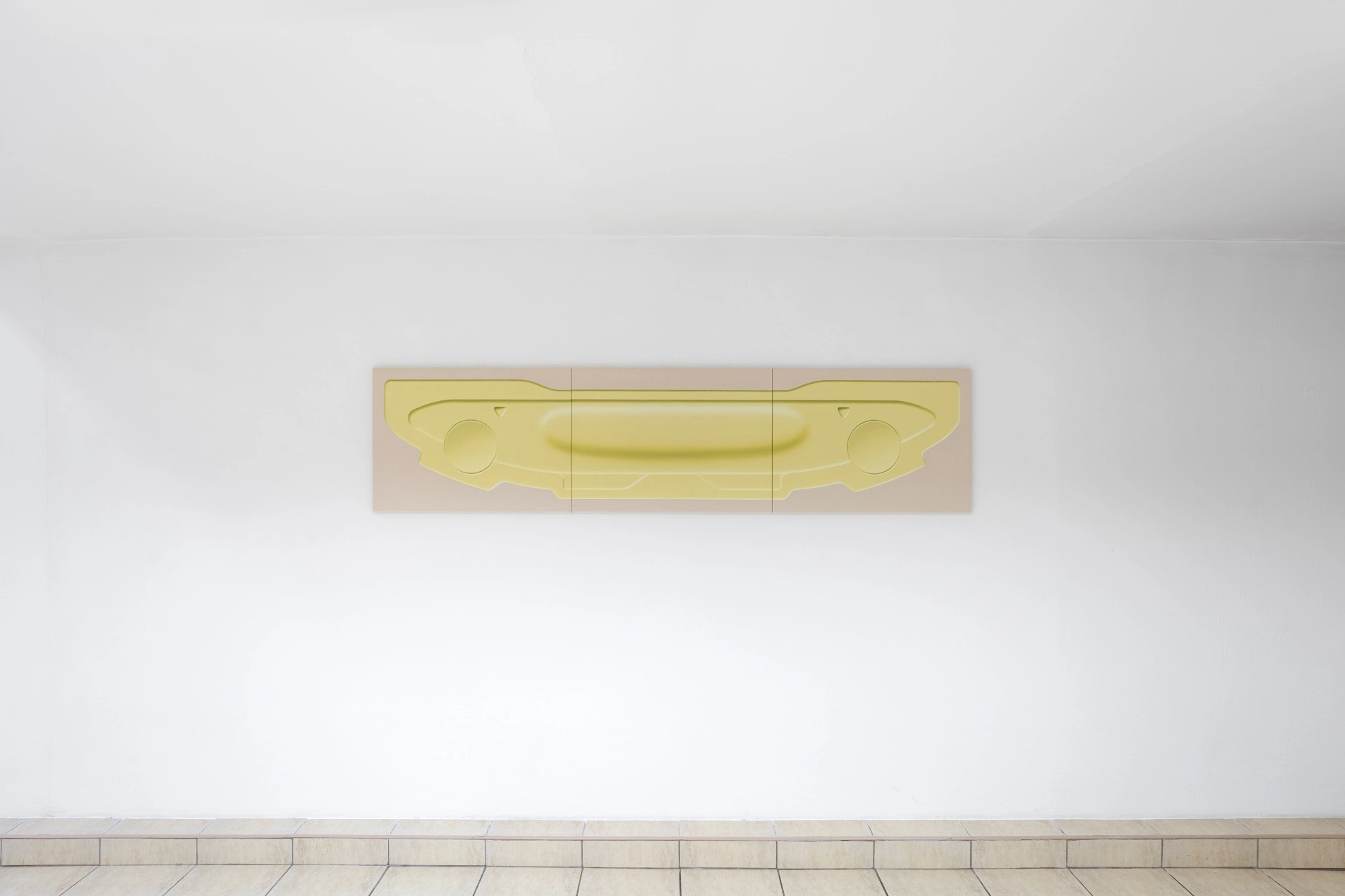 [face_not_recognized] by Milan Vagač — A horizontal wall-mounted installation featuring a yellow resin or cast polymer form suspended within a three-part wooden framework.