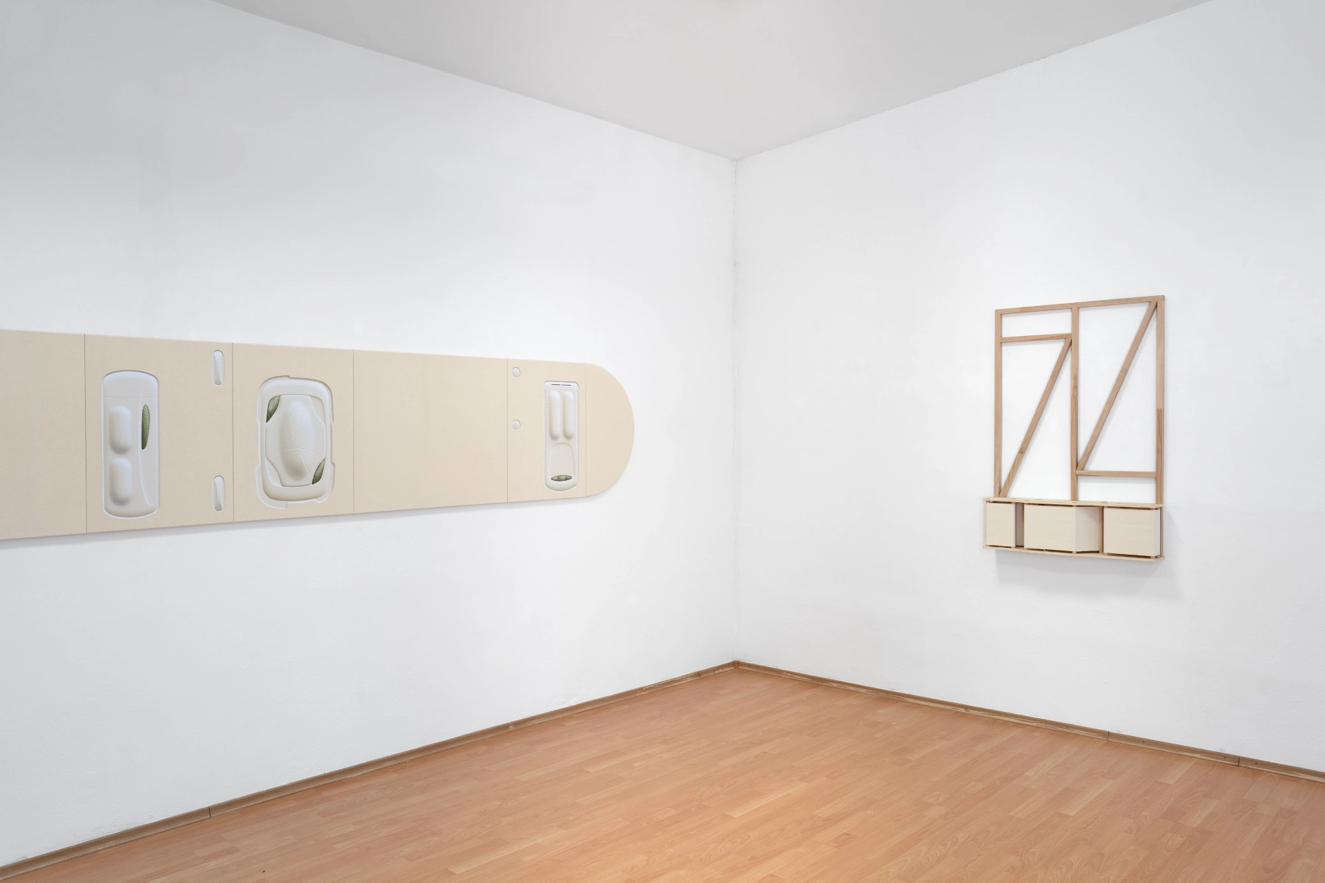 [face_not_recognized] by Milan Vagač — A gallery corner presents two wall-mounted works in pale timber and cream-toned materials.