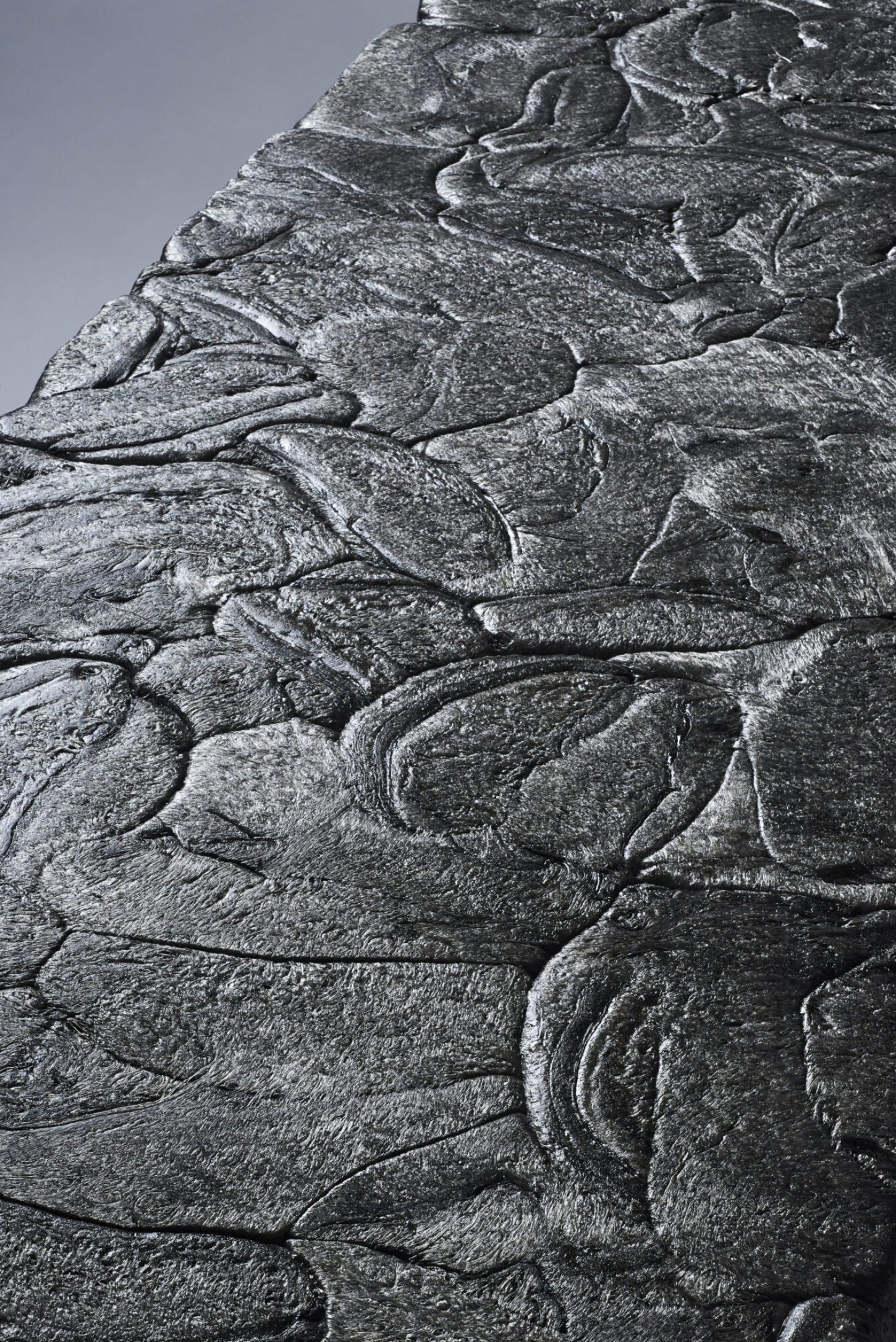 Refoam by We+ — Close-up detail of a cylindrical architectural capital carved with overlapping acanthus-leaf or scale motifs arranged in radiating rows.