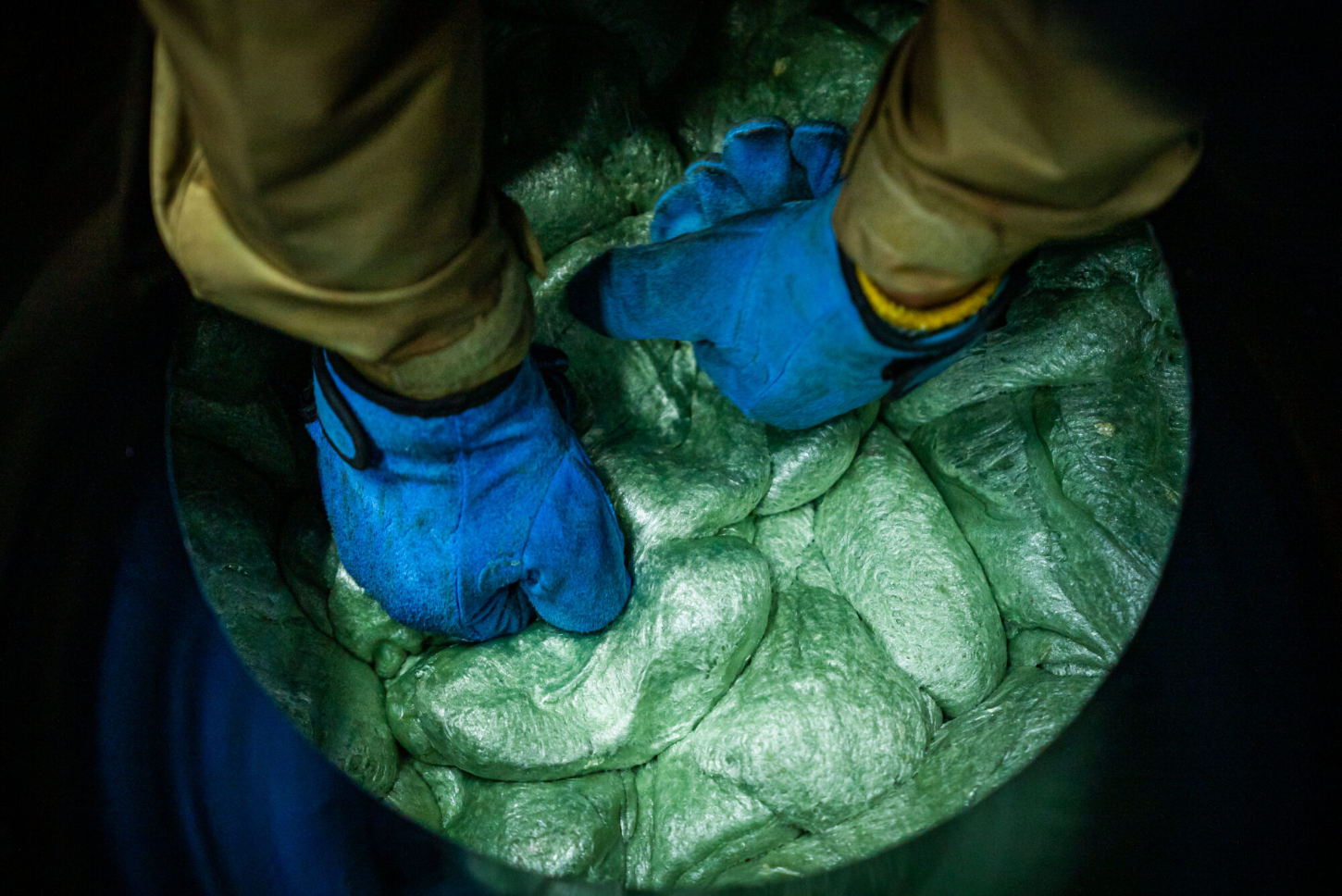 Refoam by We+ — Overhead close-up photograph capturing hands wearing blue protective gloves cradling a textured green foam or molded material.
